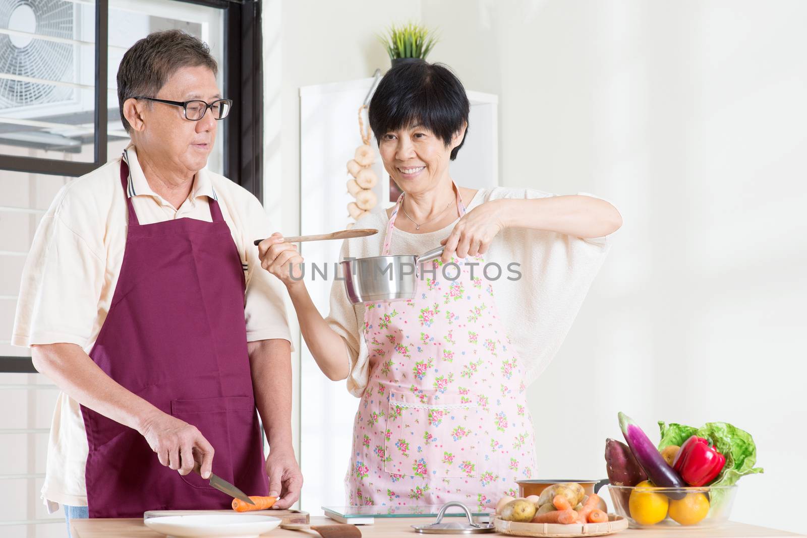 Asian mature couple cooking meal at kitchen. Seniors living lifestyle at home.