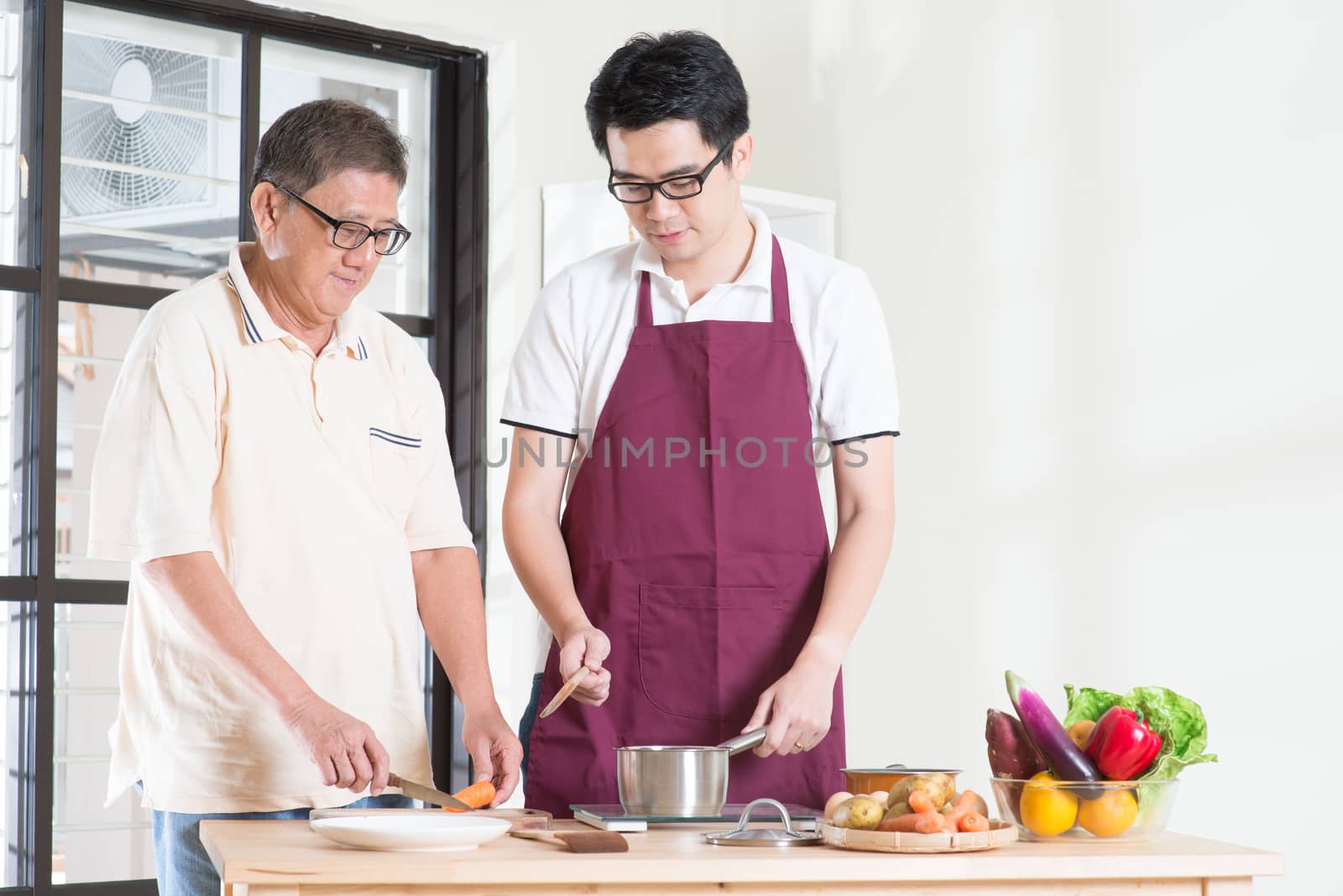 Asian senior father and adult son cooking meal at kitchen. Family living lifestyle at home.