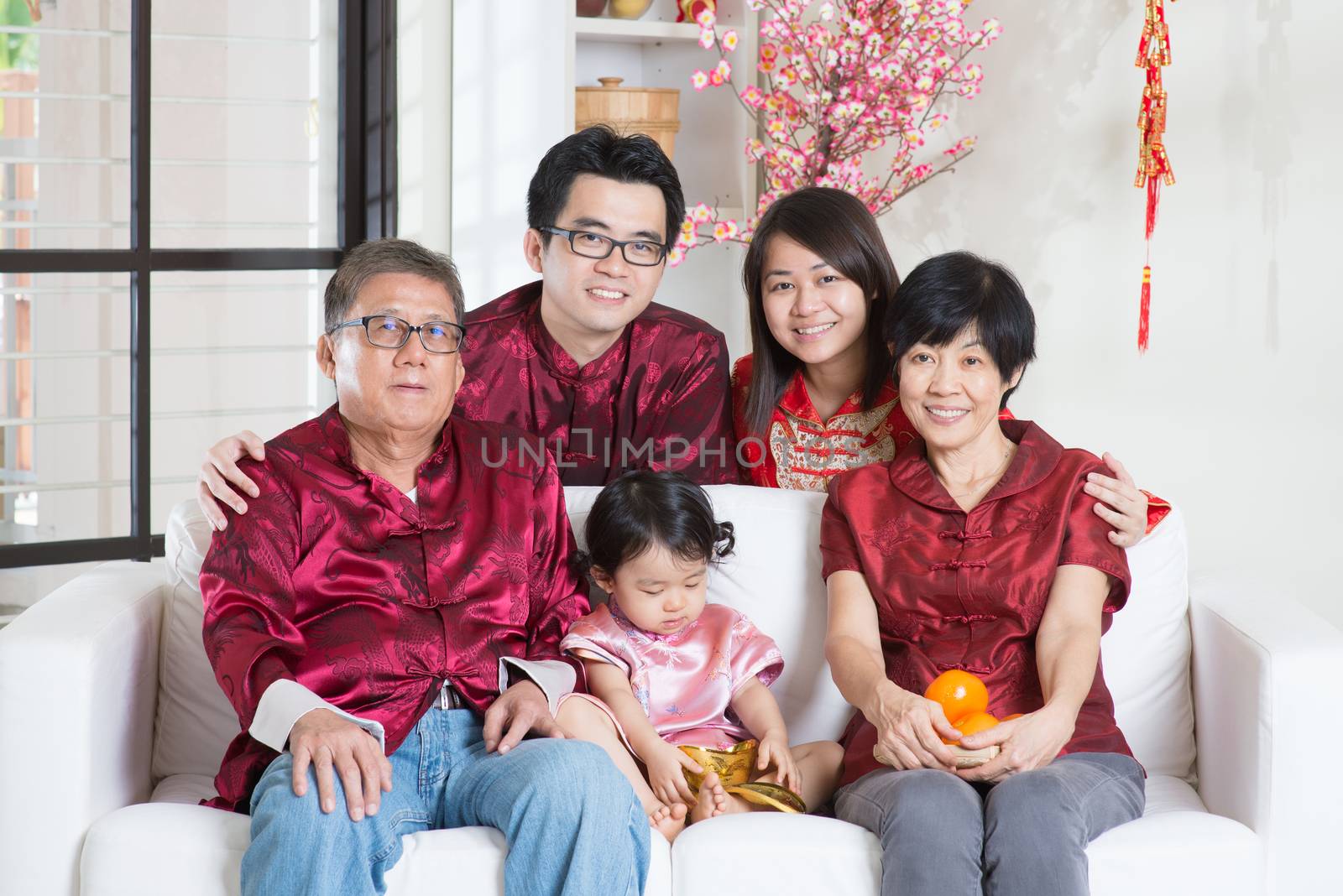 Chinese new year celebration. Happy Asian multi generations family in red cheongsam reunion at home.