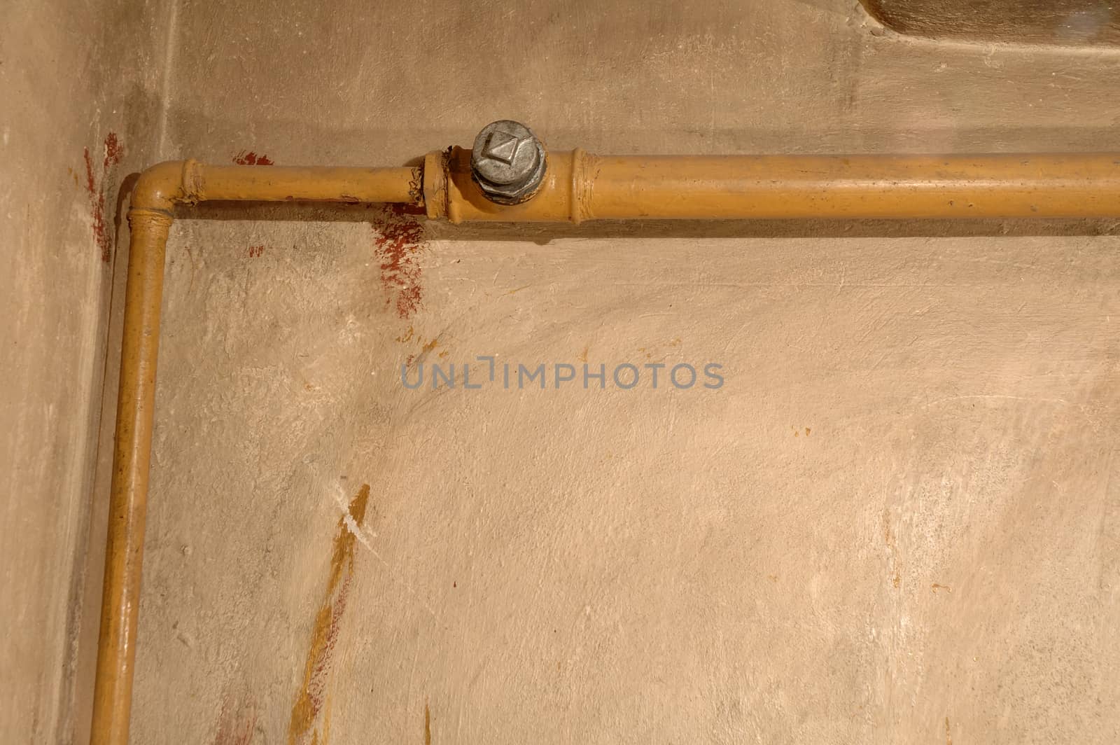 Old yellow pipe and dirty wall in old boiler room