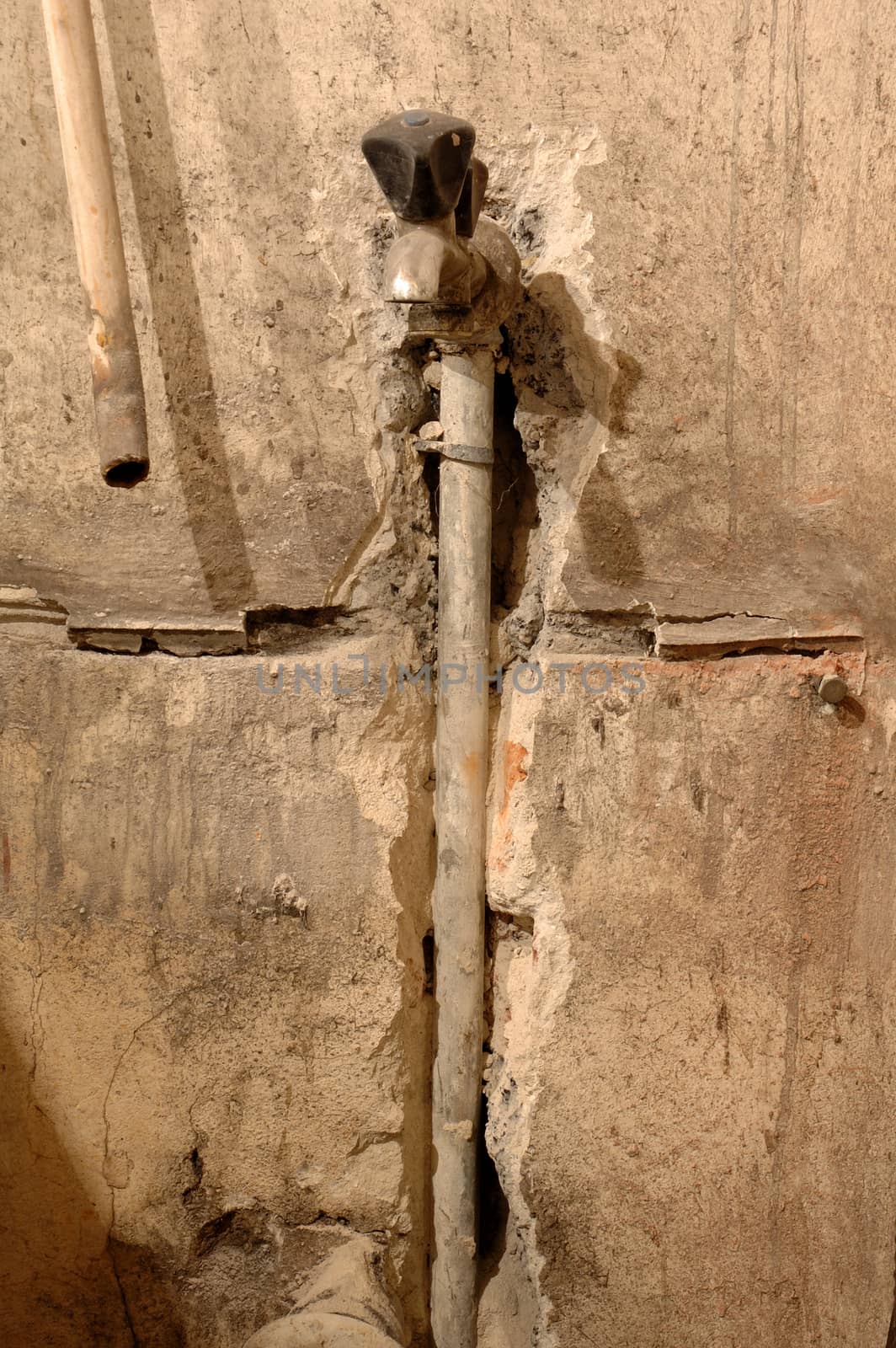 Old cock and pipe inside old dirty wall