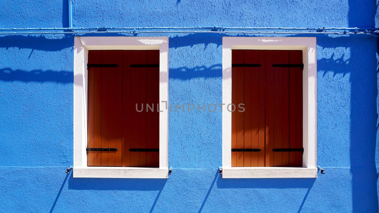 wood window with white frame on blue color wall house in Burano, Venice, Italy