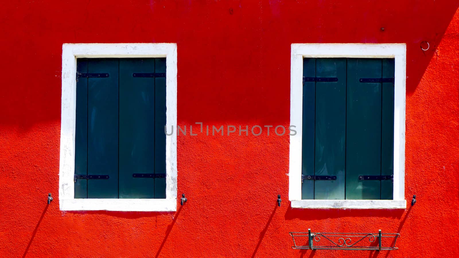 two windows with white frame on red color wall in Burano Island, Venice, Italy