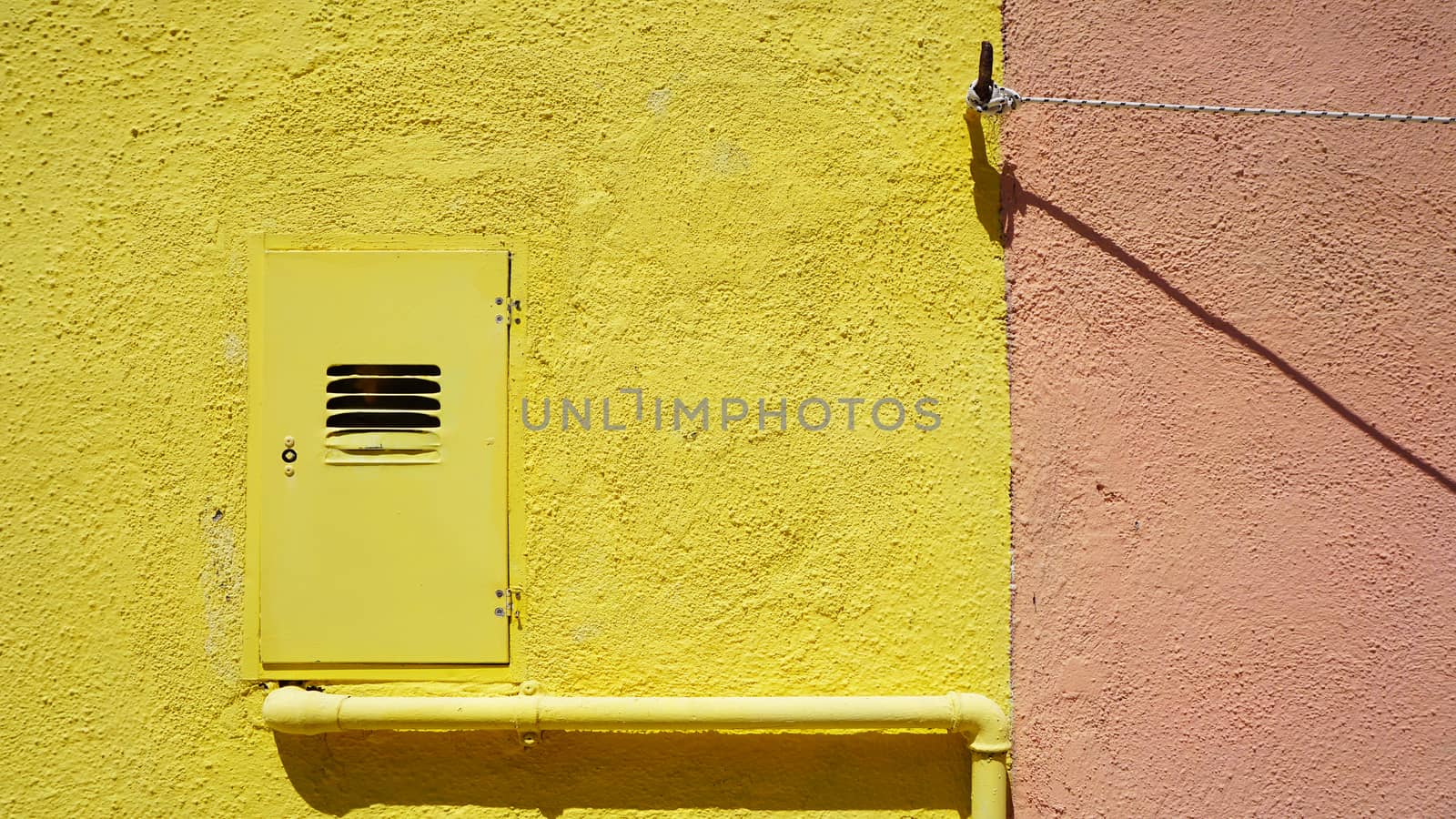 metal pipe and electric box on yellow color wall in Burano, Venice, Italy