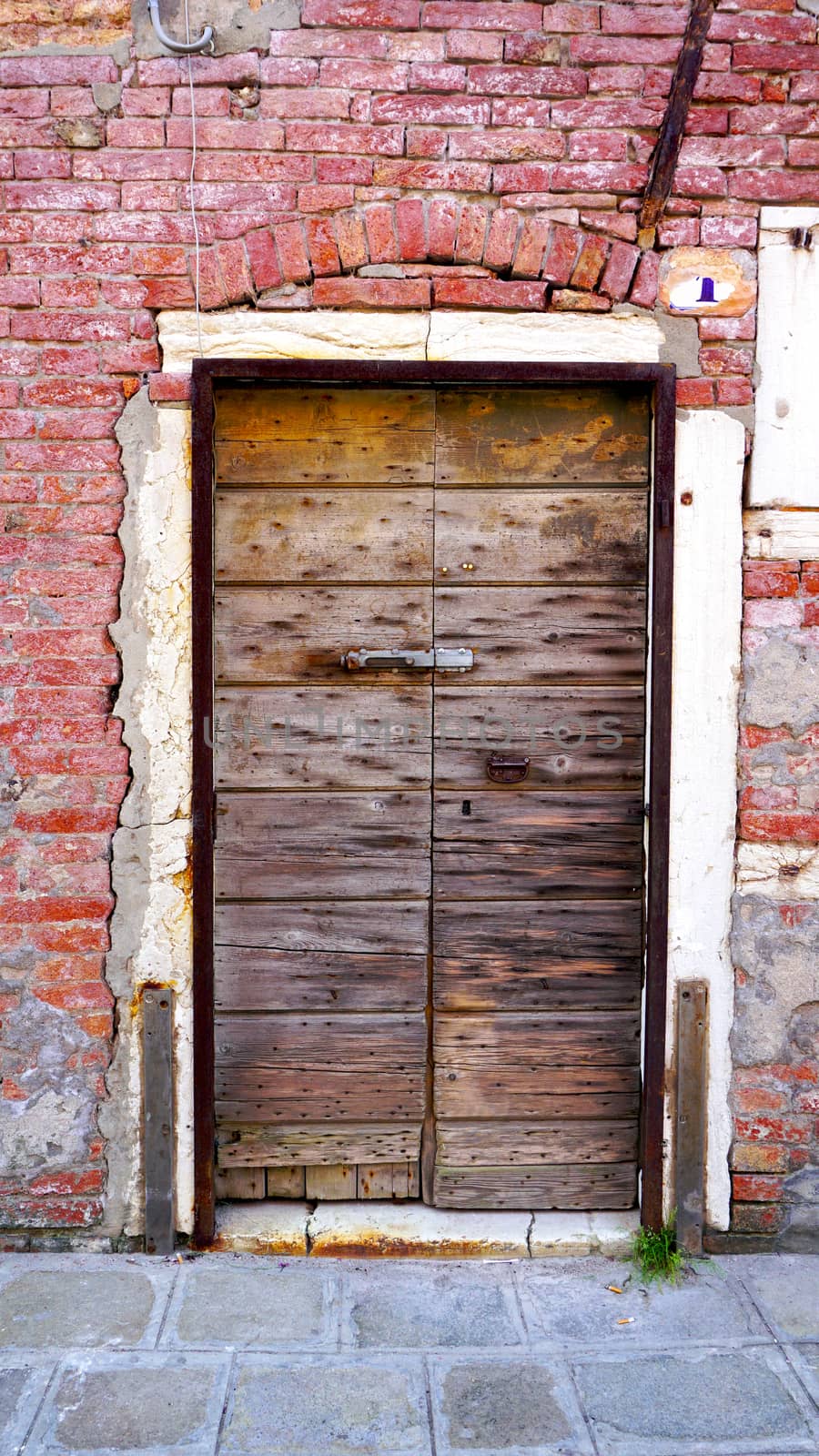 antique wooden door and old brick wall in Murano, Venice, Italy