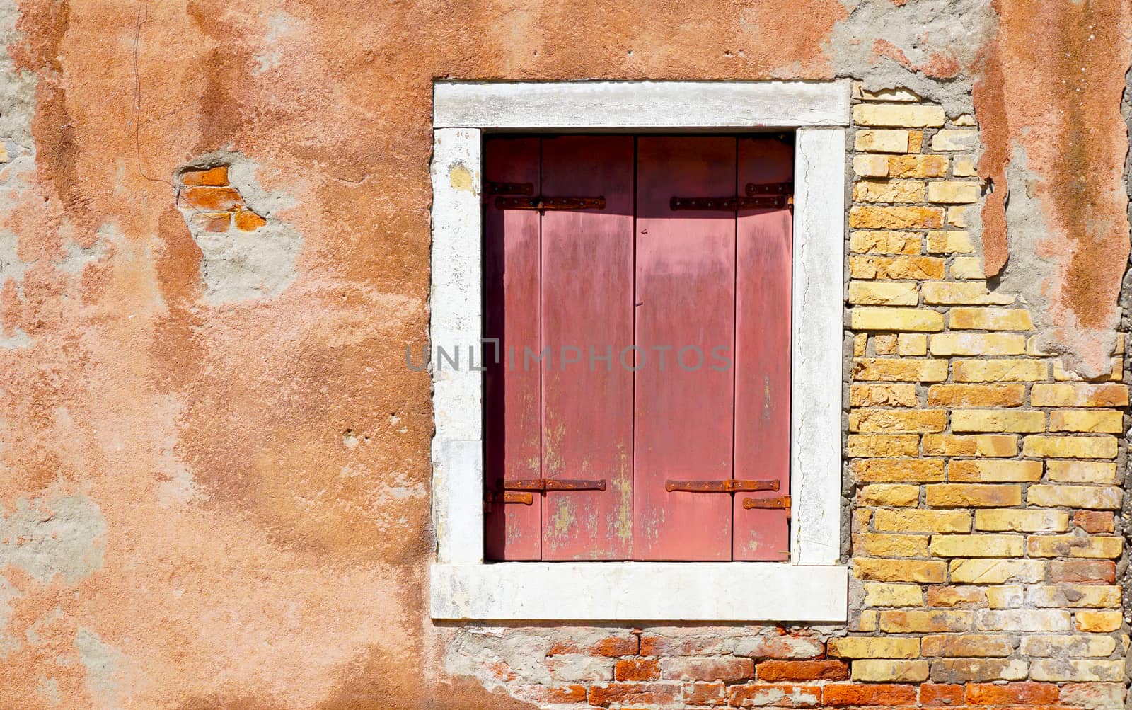 red window in white frame and ancient decay wall building architecture in Murano, Venice, Italy