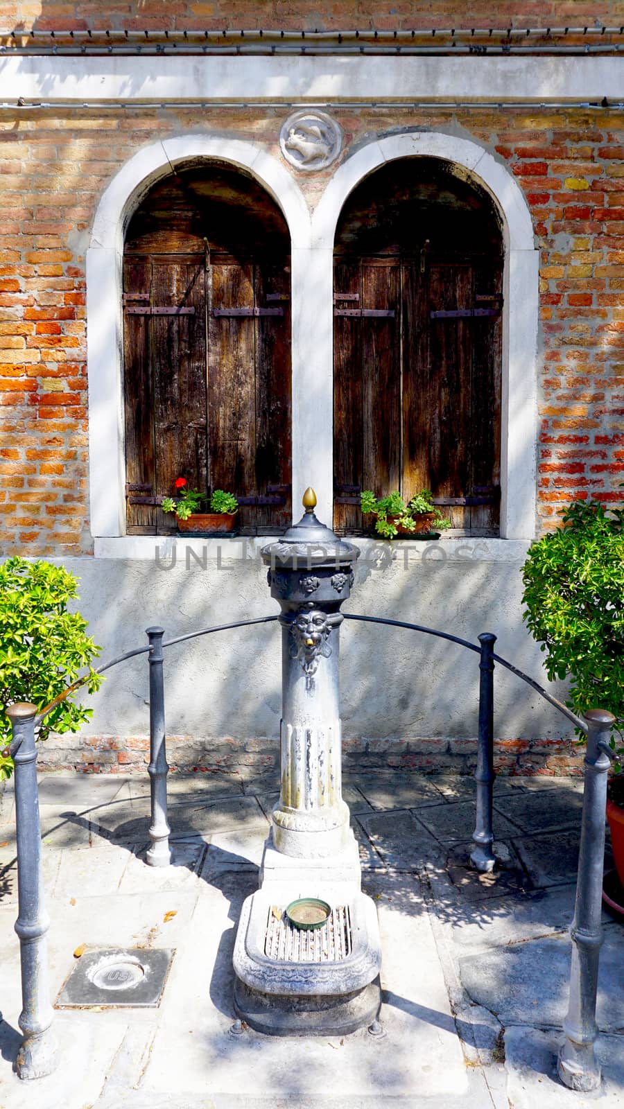 drinking water point with two windows background in Murano, Venice, Italy 