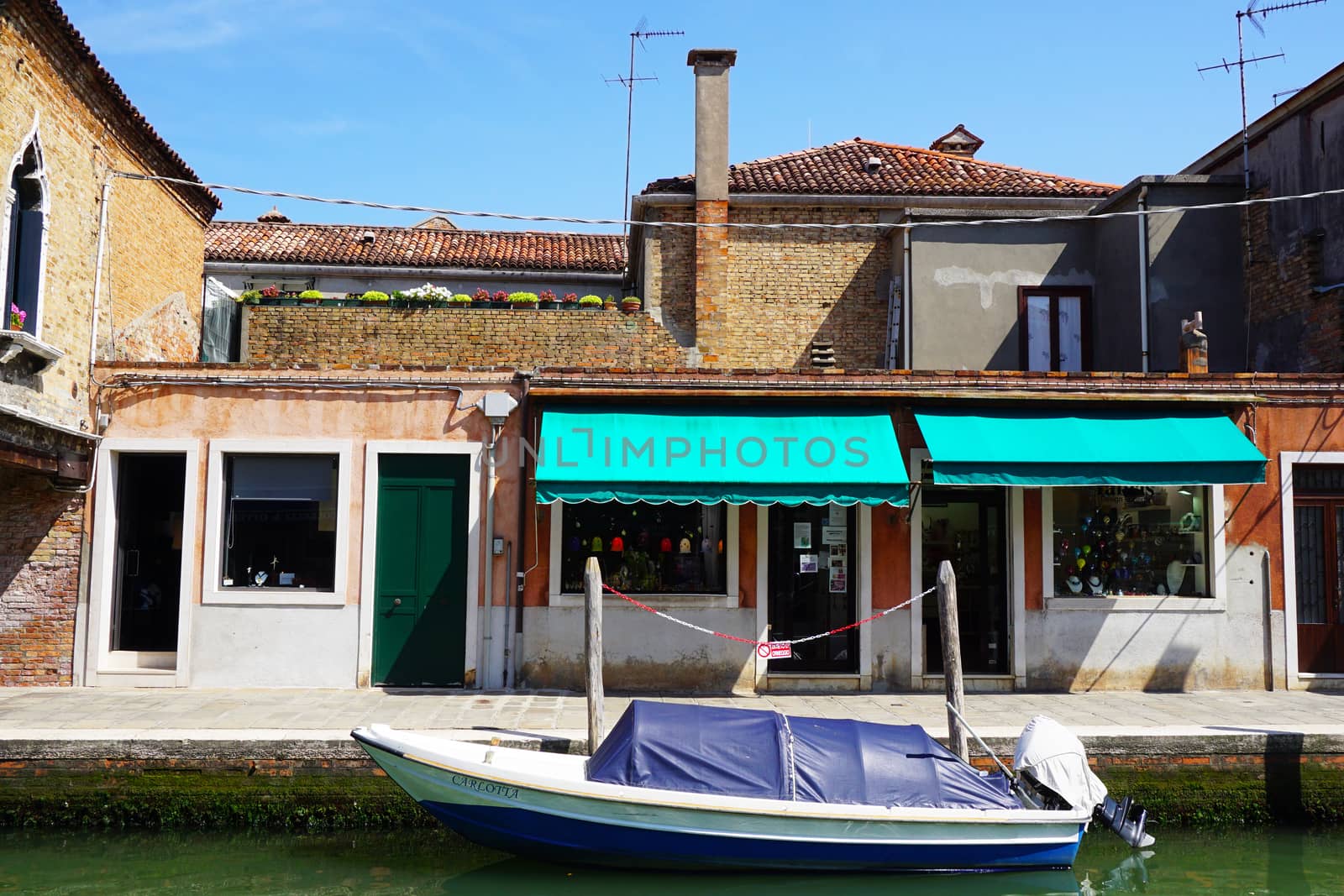 front building architecture with canal and boat in Murano, Venice, Italy