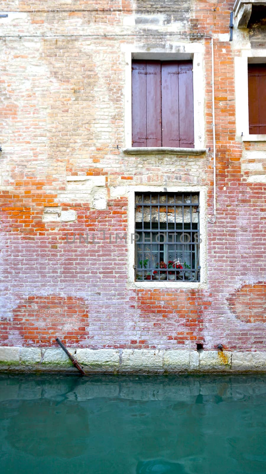 ancient brick wall of building and canal in Venice, Italy