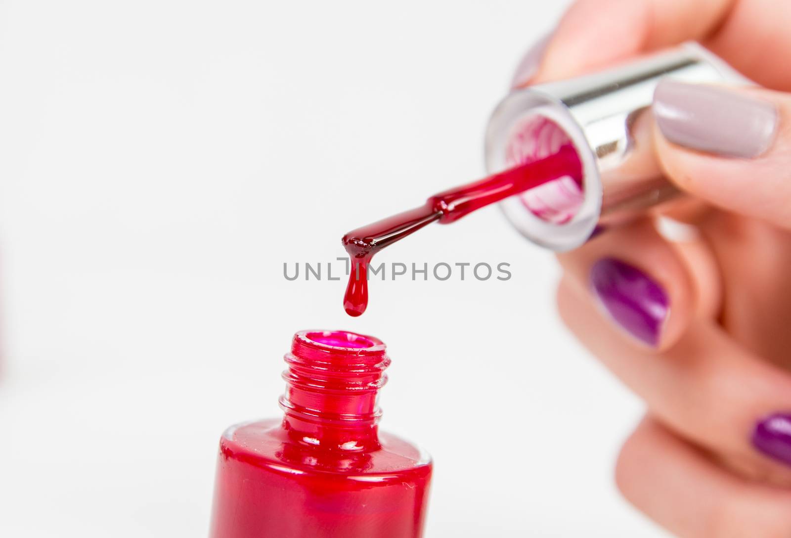 Red nail polish dropping in nail polish bottle on white background