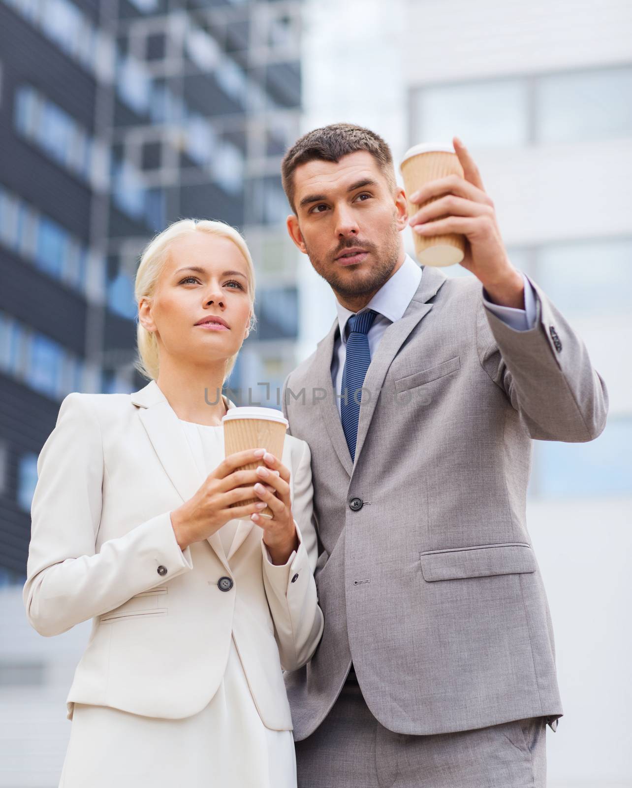 business, partnership, hot drinks and people concept - serious businessmen with paper cups standing over office building