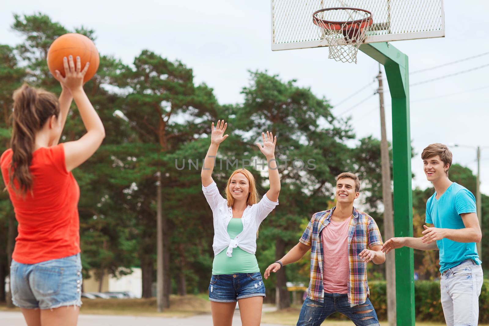 summer vacation, holidays, games and friendship concept - group of smiling teenagers playing basketball outdoors
