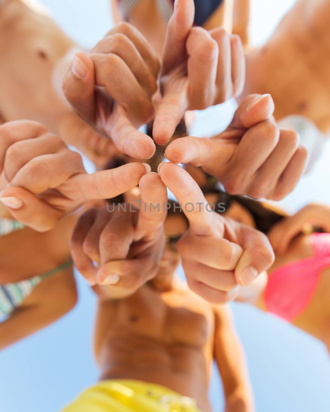 close up of friends in circle on summer beach by dolgachov