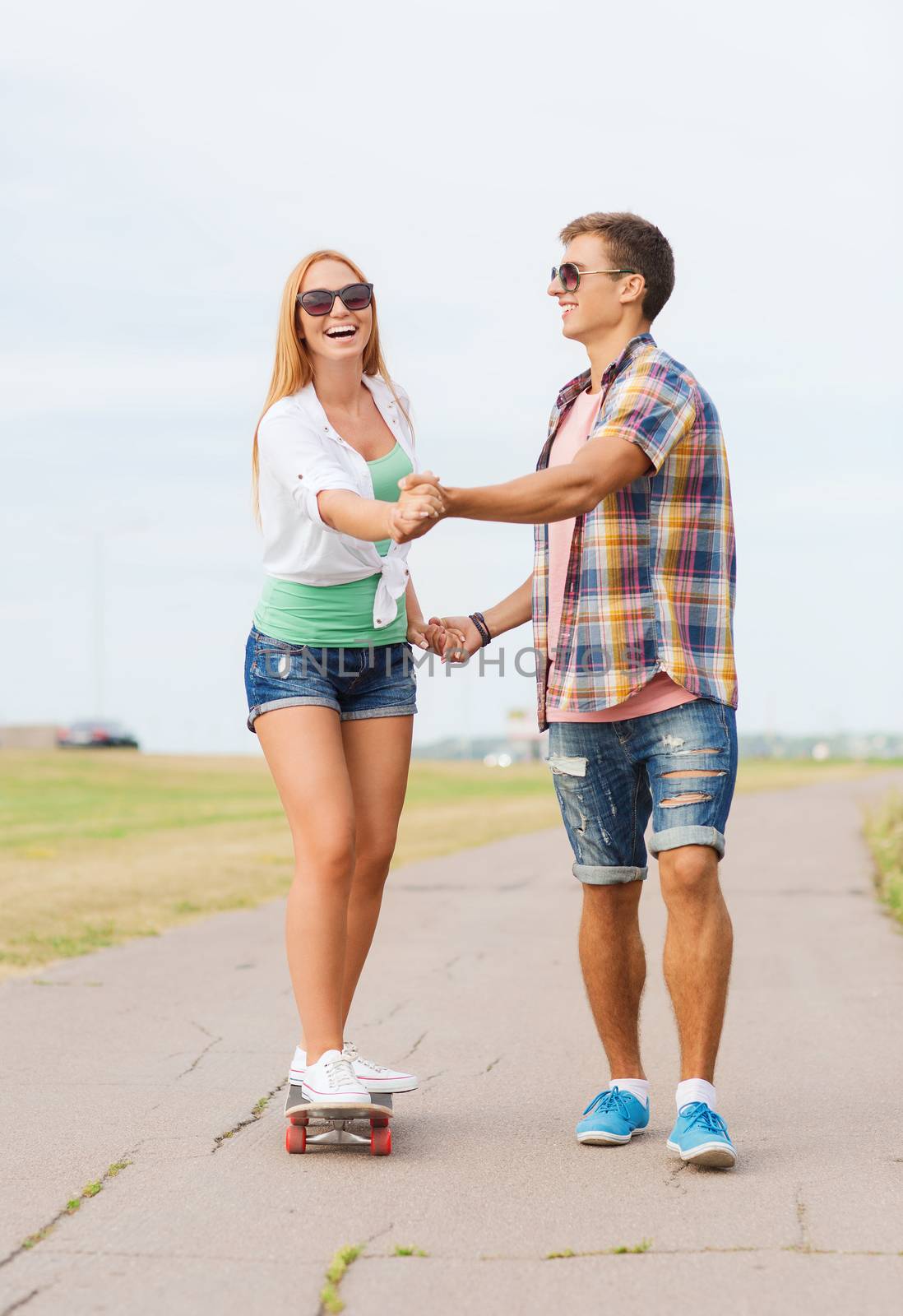 smiling couple with skateboard outdoors by dolgachov