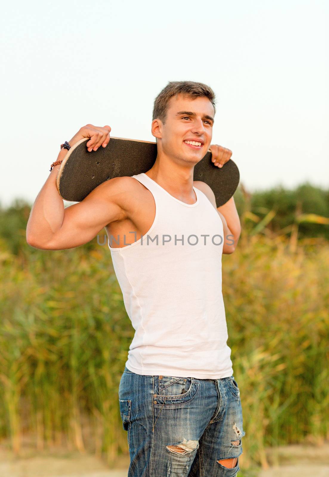 smiling teenage boy with skateboard outdoors by dolgachov