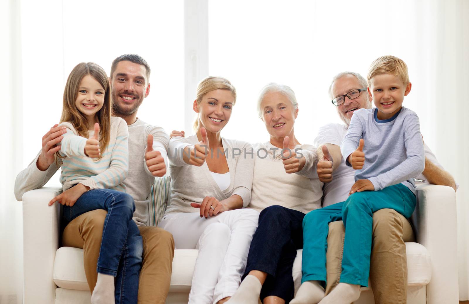 happy family sitting on couch at home by dolgachov