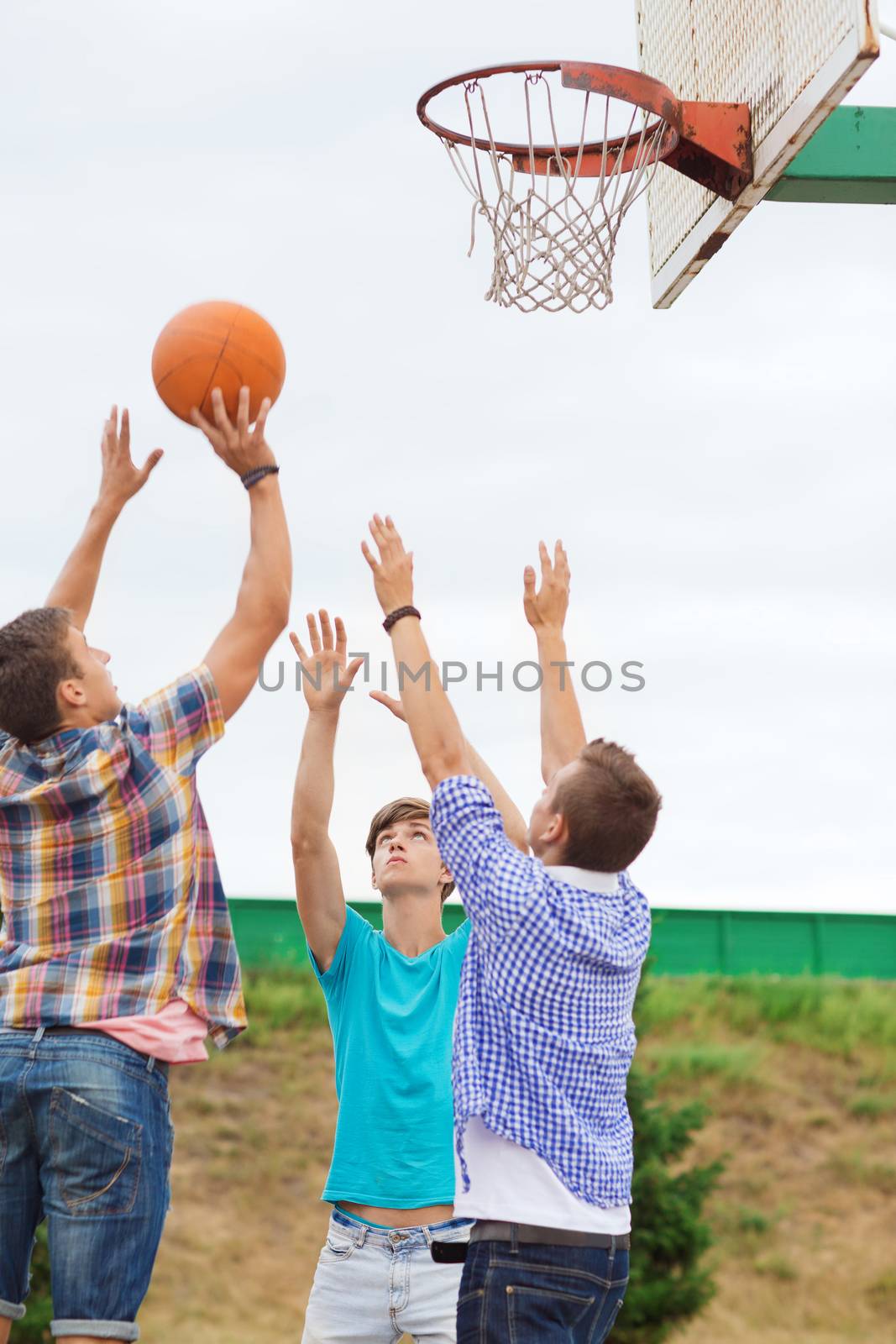 summer vacation, holidays, games and friendship concept - group of teenagers playing basketball outdoors