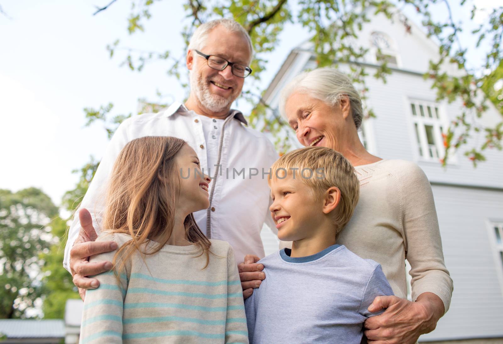 family, happiness, generation, home and people concept - happy family standing in front of house outdoors