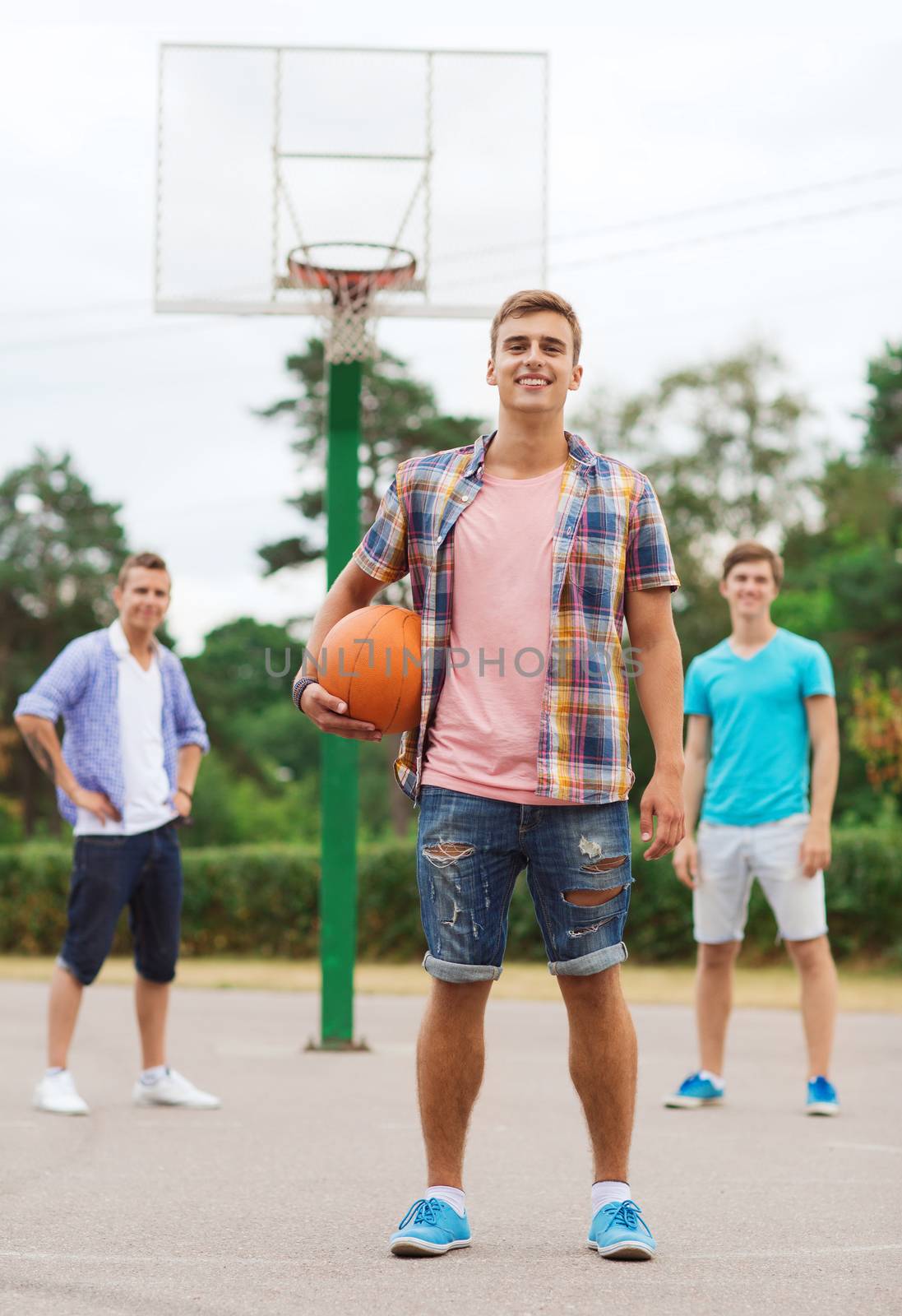 summer vacation, holidays, games and friendship concept - group of smiling teenagers playing basketball outdoors