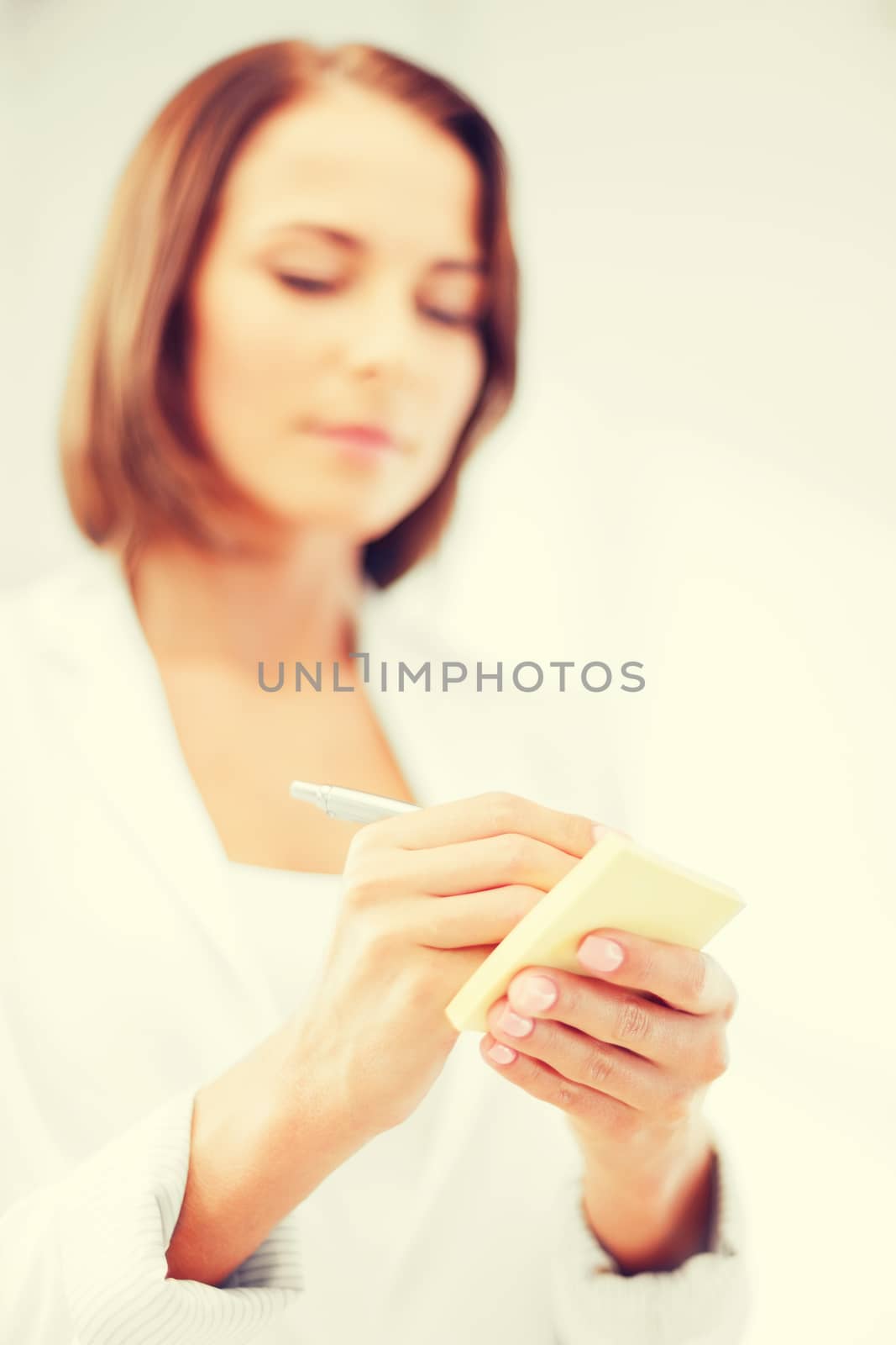 business, office, school and education concept - businesswoman writing on sticky note