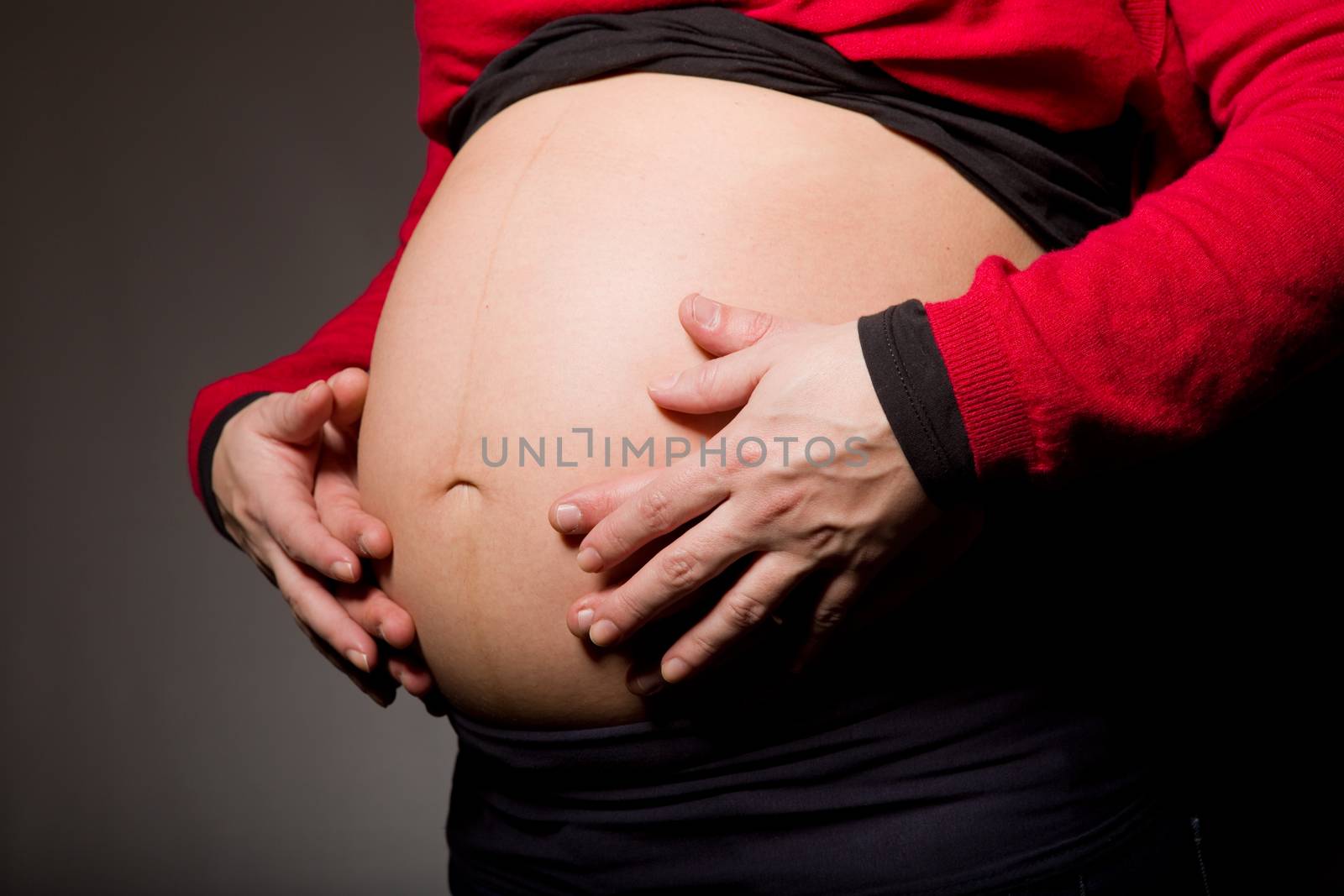 hands embrace a belly of the pregnant woman