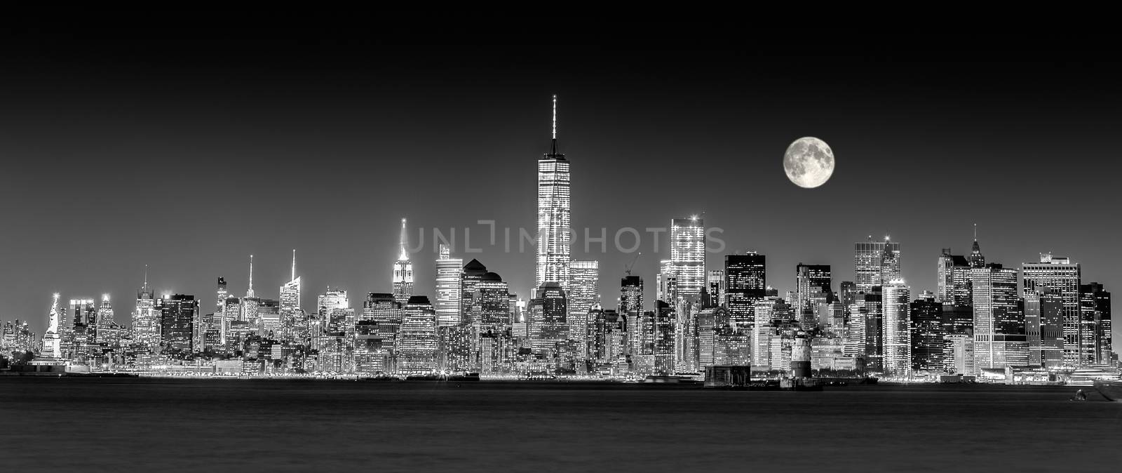 New York City Manhattan downtown skyline at dusk with skyscrapers illuminated over Hudson River panorama. Horizontal composition, copy space. Black and white image.