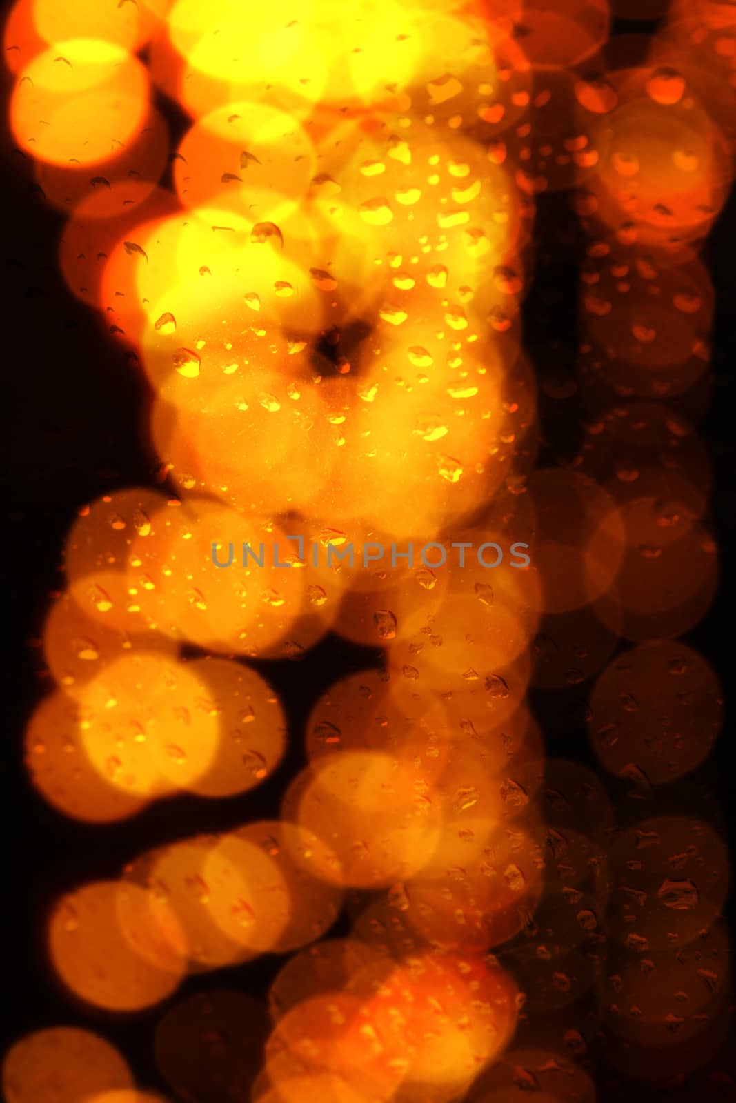 An abstract background of a glass pane with droplets with a droplet of festive lights