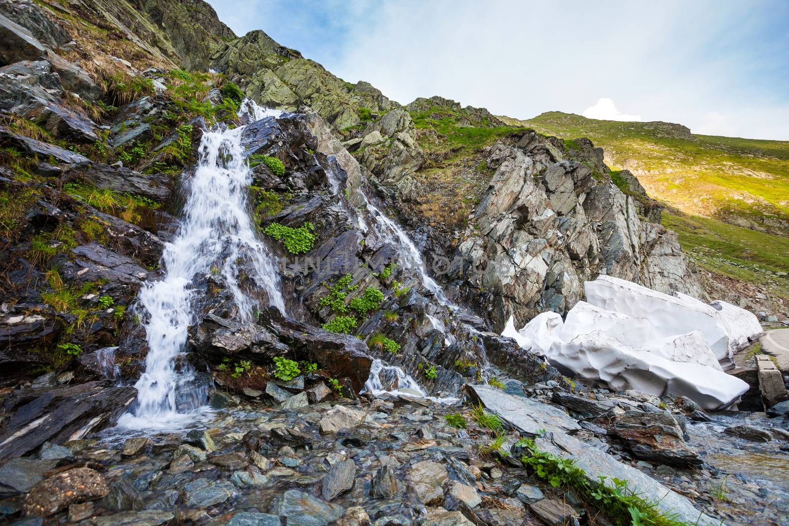 River watterfall flowing over rough rocks and snow left unmeltd