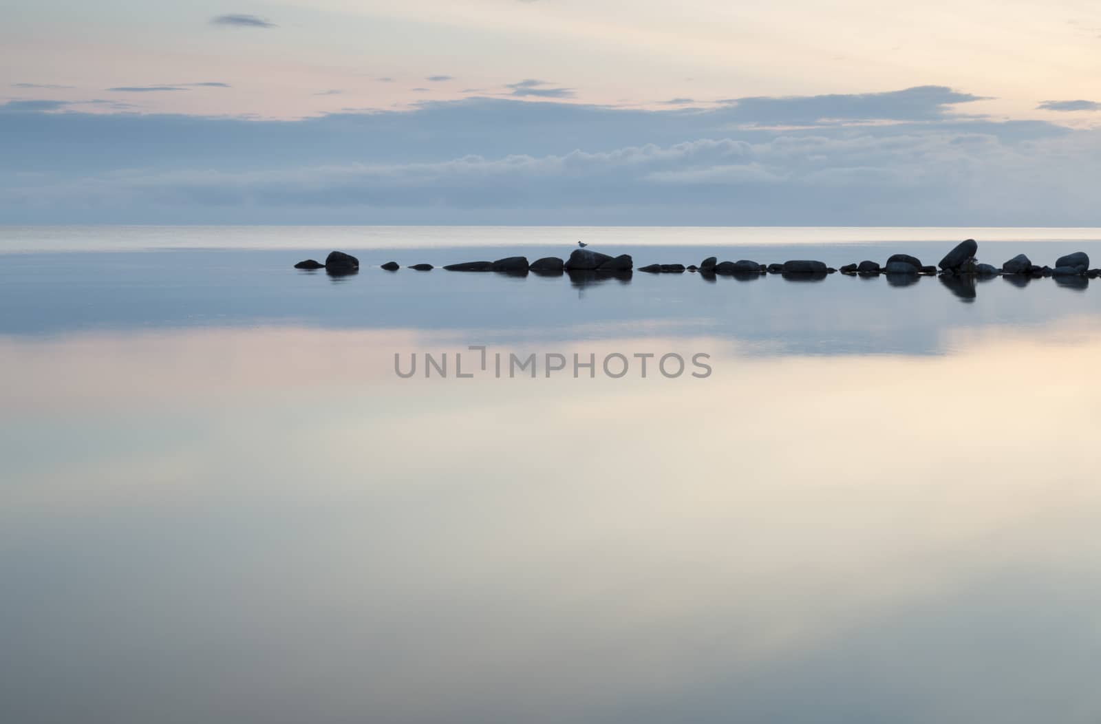 Breakwater Rocks in Calm Sea with clouds and reflextions in the water.