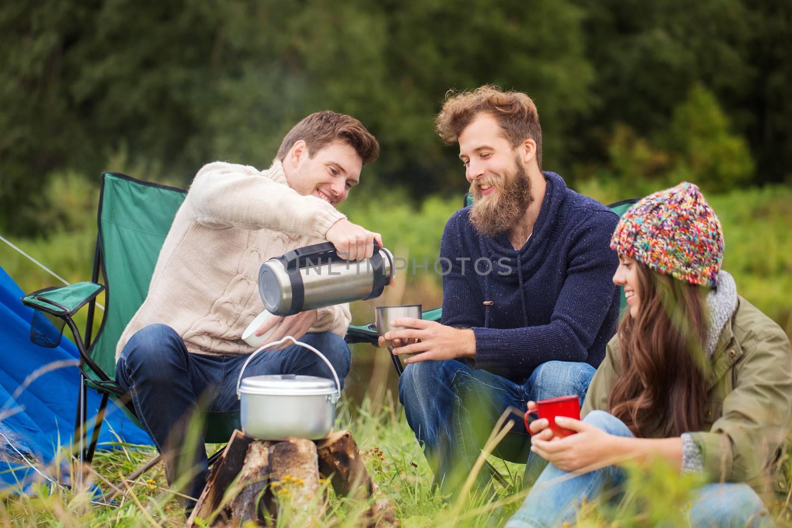 group of smiling friends cooking food outdoors by dolgachov