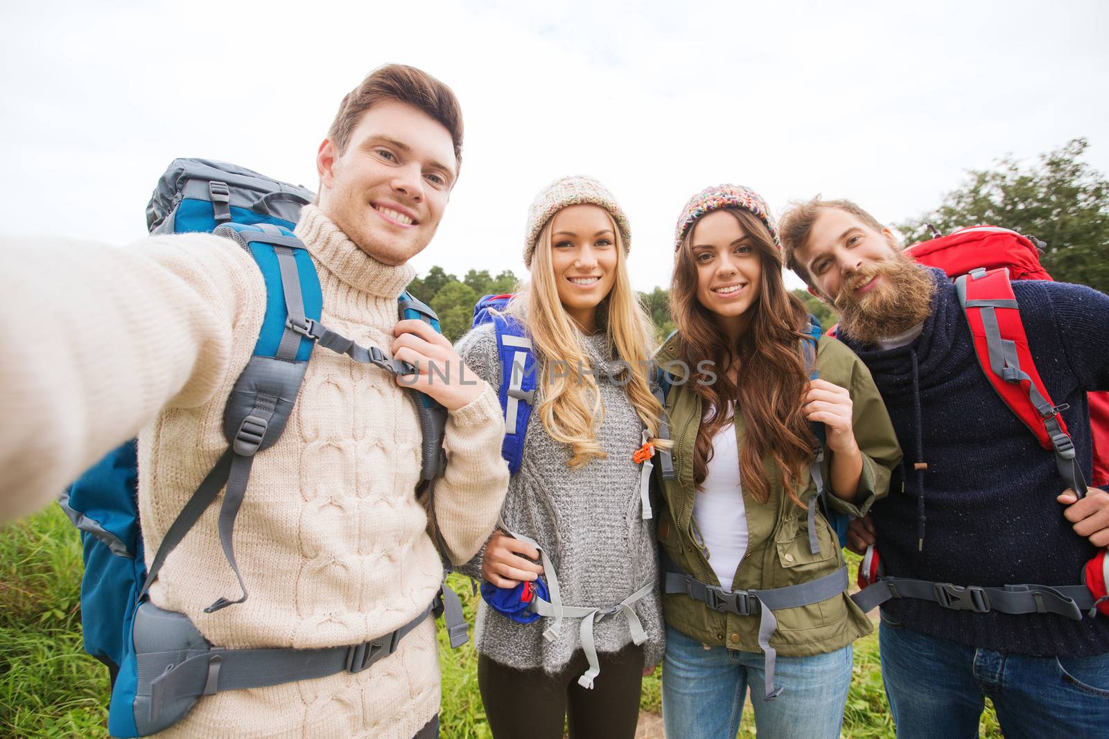 group of smiling friends with backpacks hiking by dolgachov