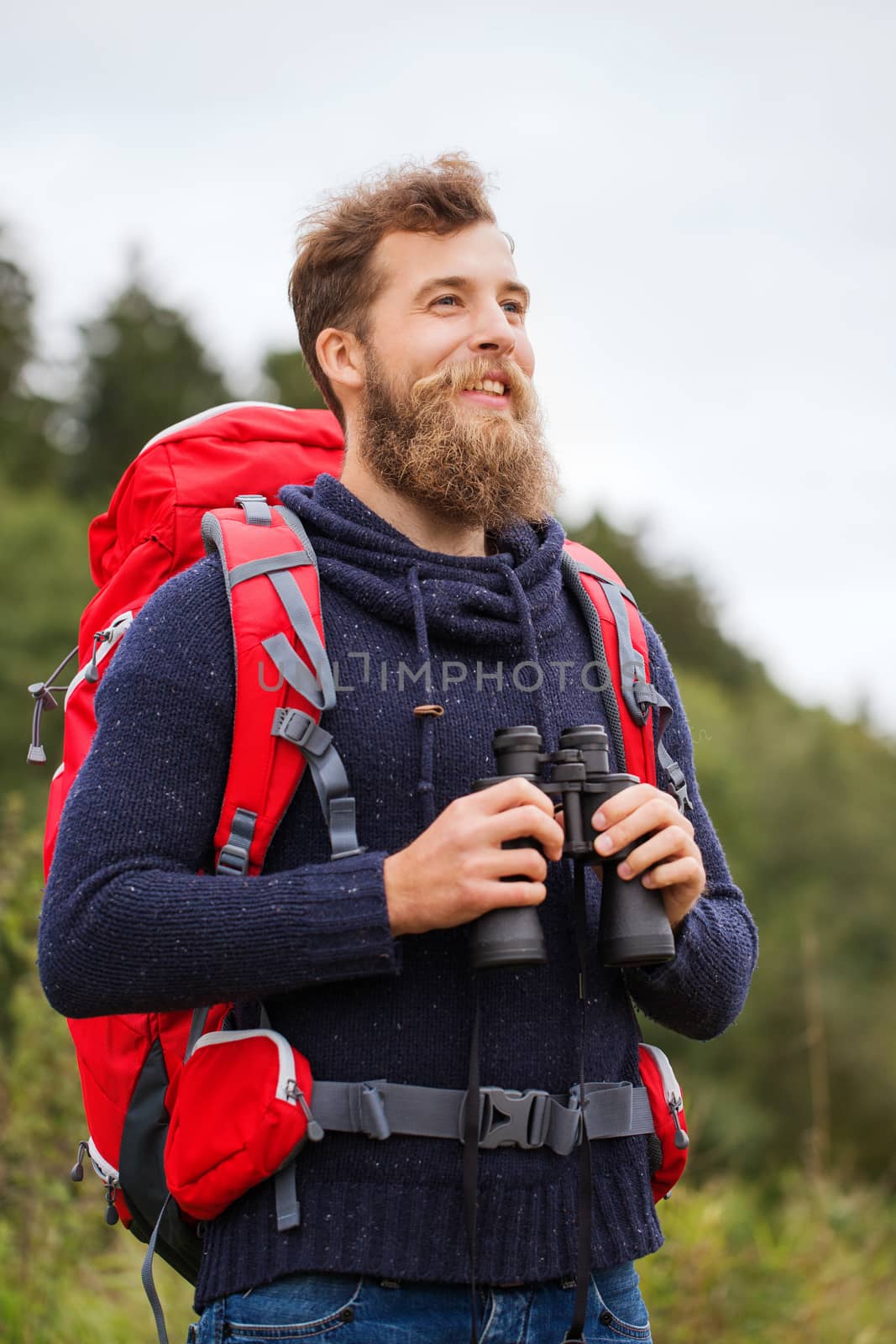 adventure, travel, tourism, hike and people concept - smiling man with red backpack and binocular outdoors