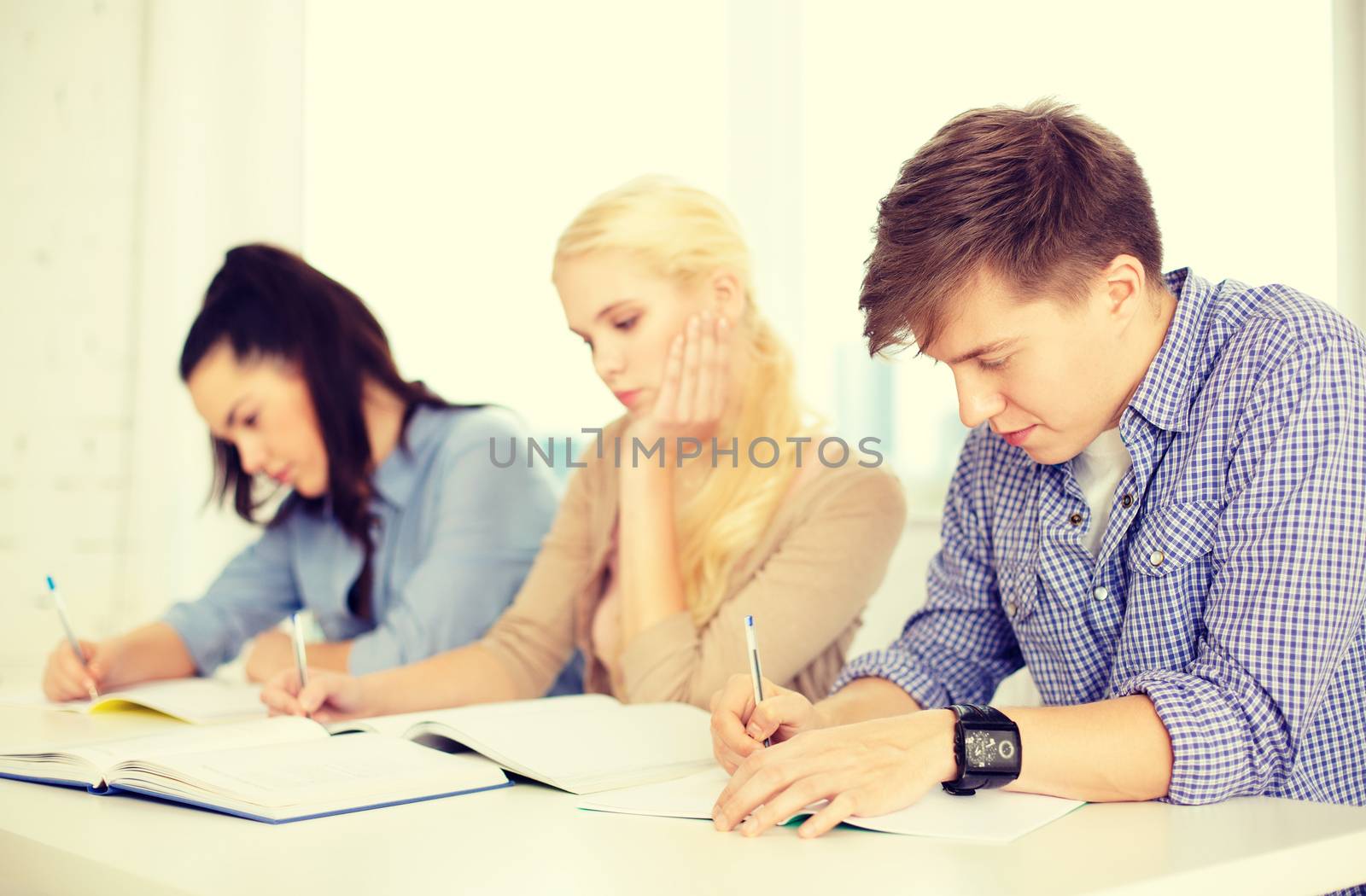 school and education concept - group of tired students with notebooks at school