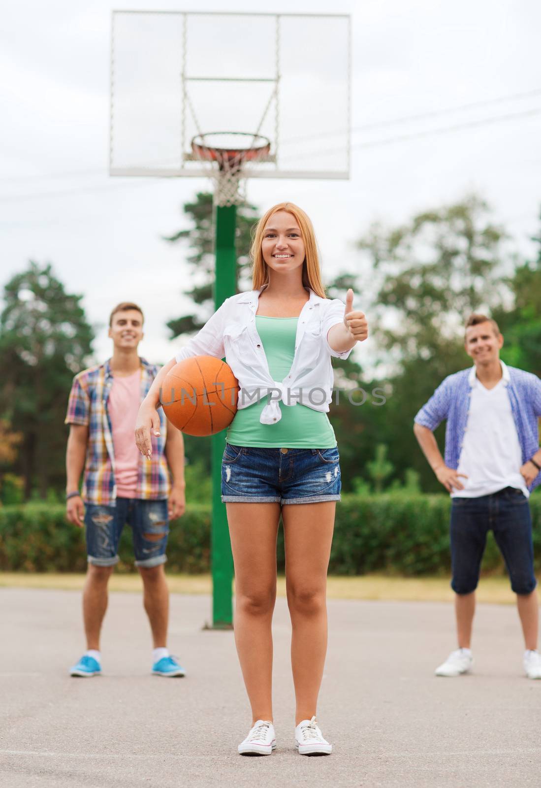 group of smiling teenagers playing basketball by dolgachov