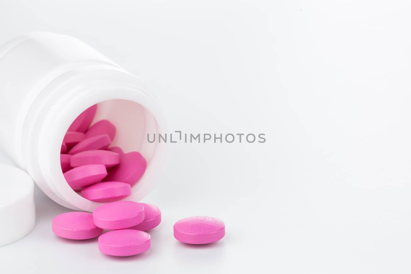 pink pills an pill bottle on white background by urubank