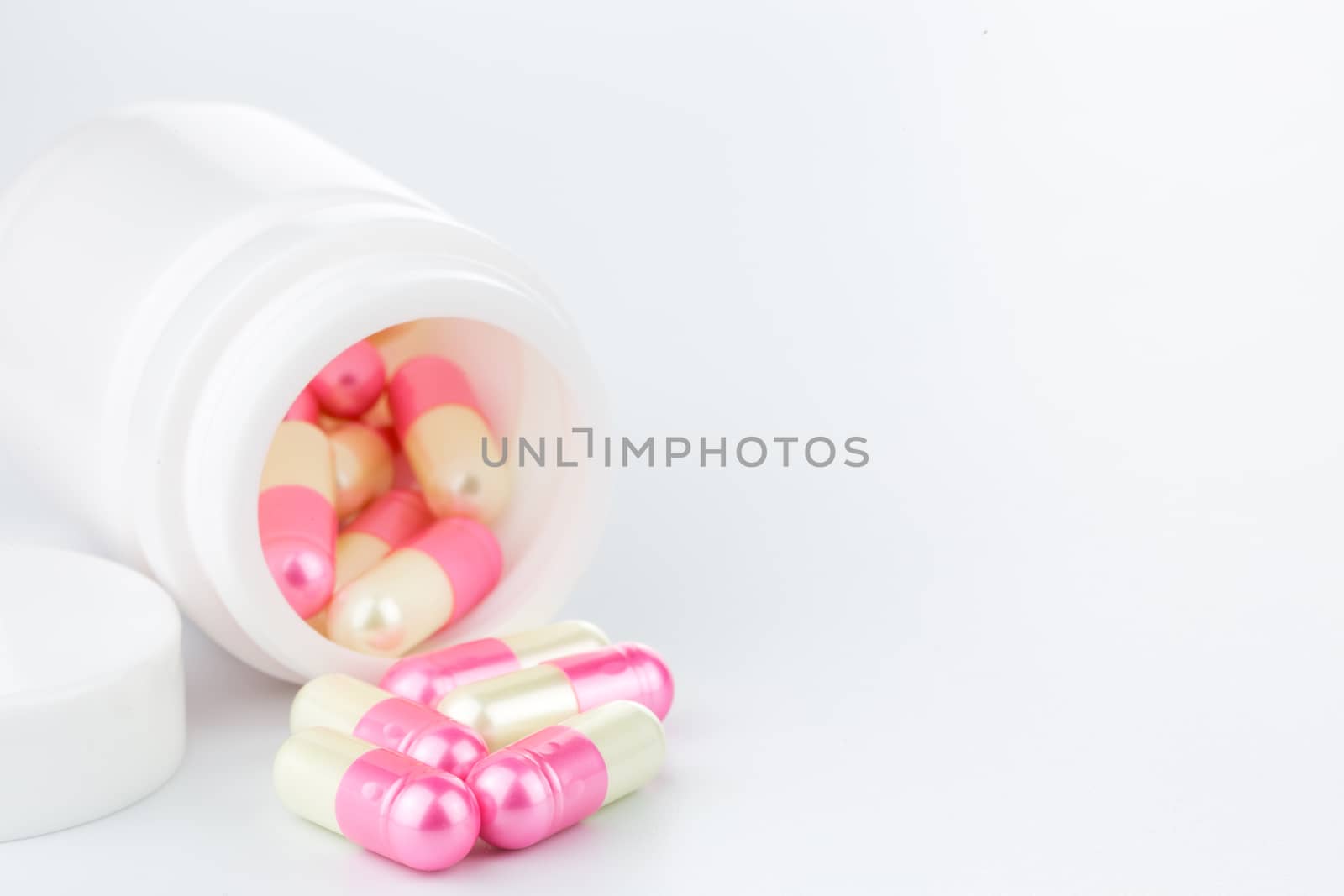 Pink and yellow pearl pills an pill bottle on white background (Isolated)