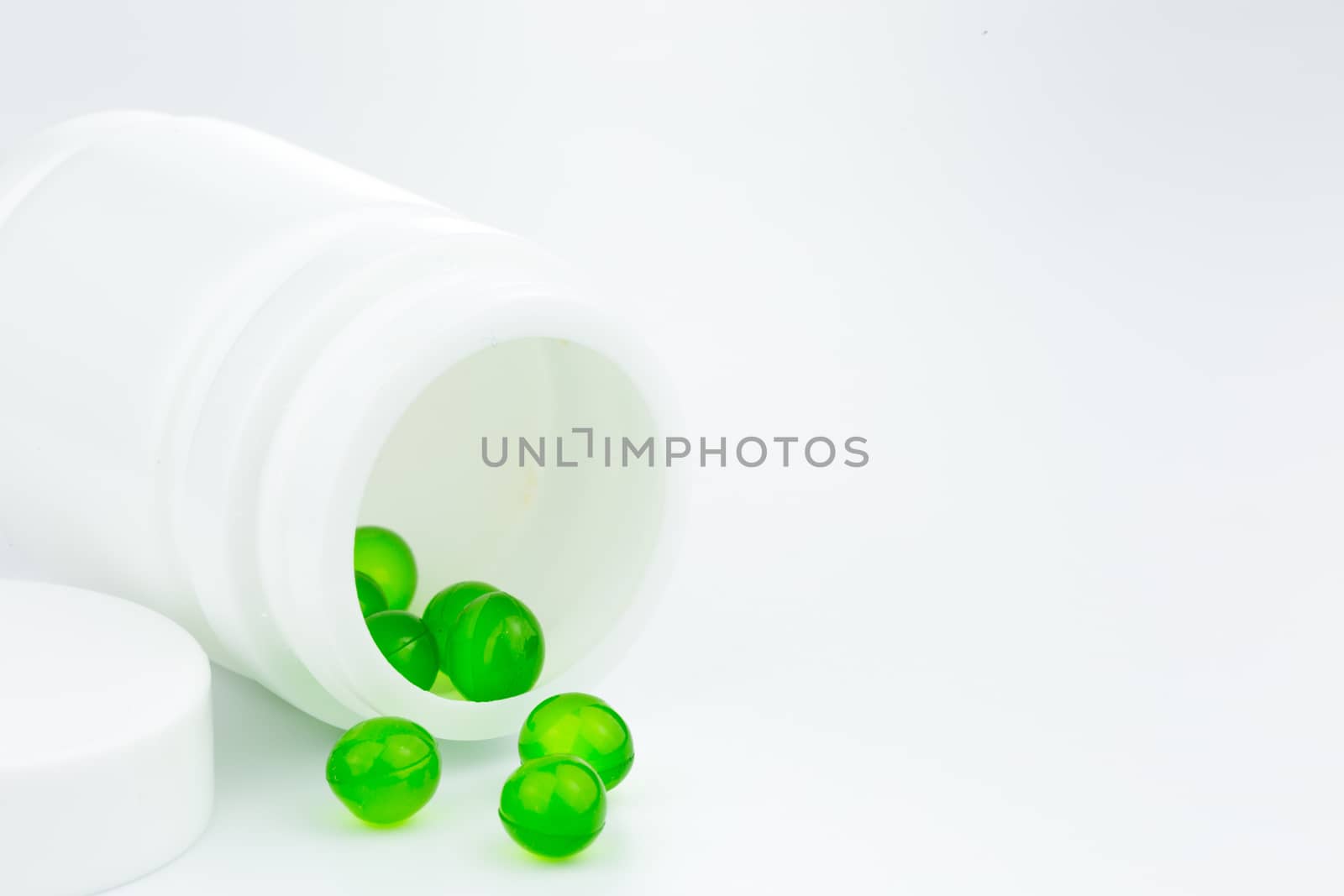 green gel pills an pill bottle on white background by urubank