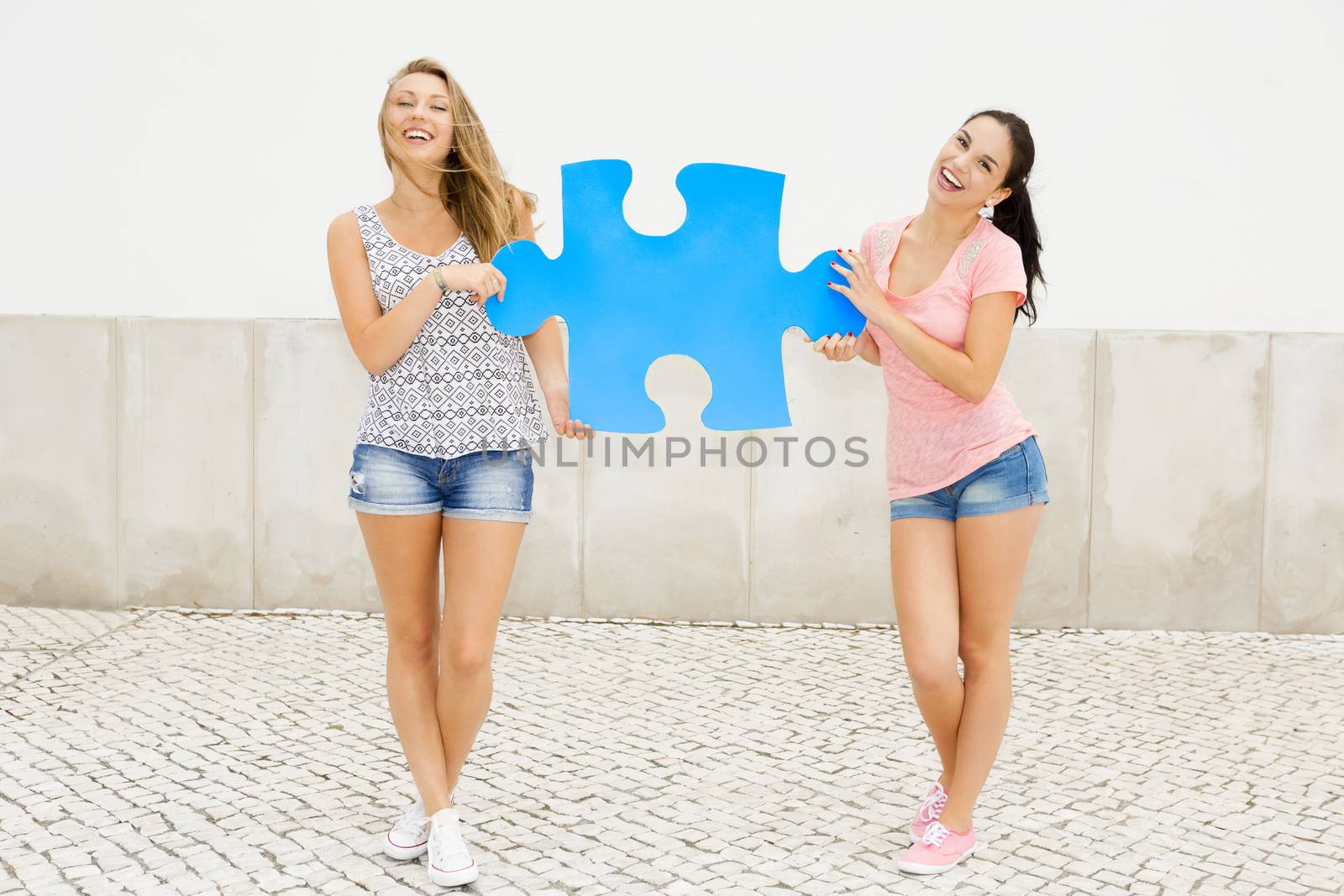 Two happy girls holding a giant puzzle piece 