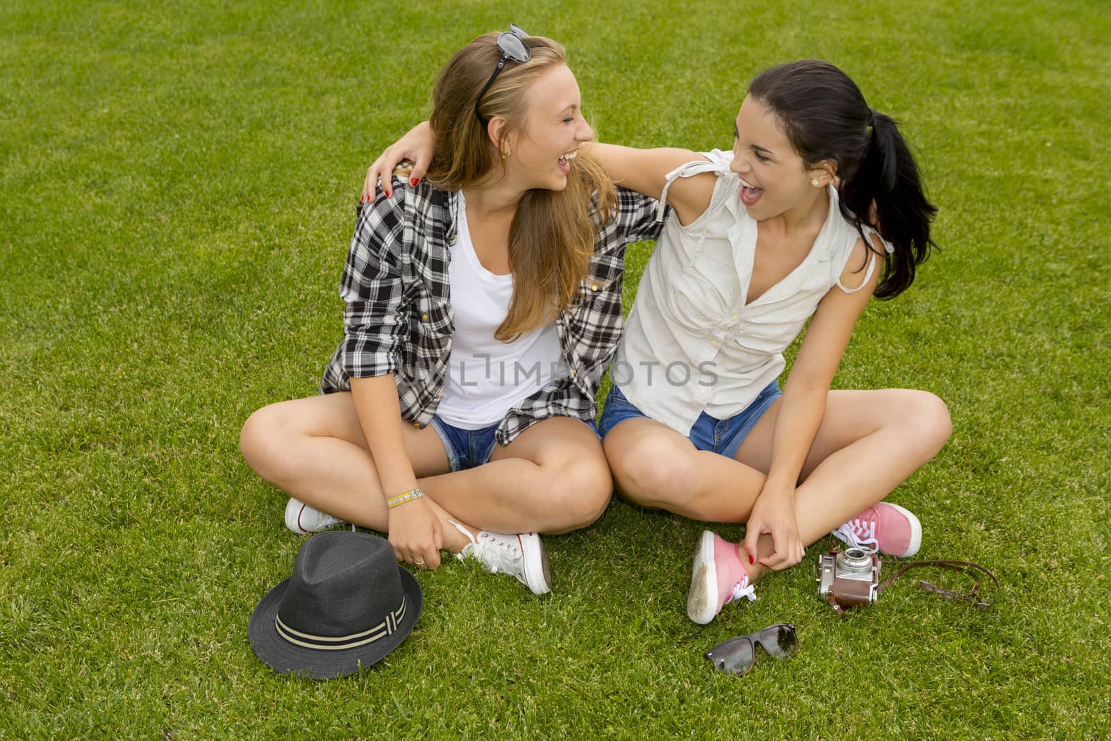 Female best friends sitting on the grass and having a good time