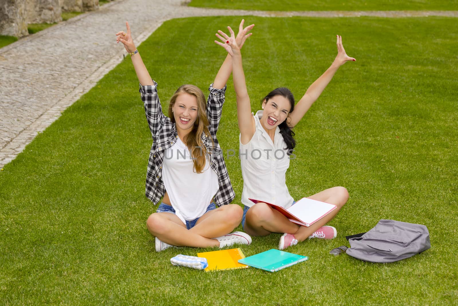 Happy best friends sitting on the grass and having a good time