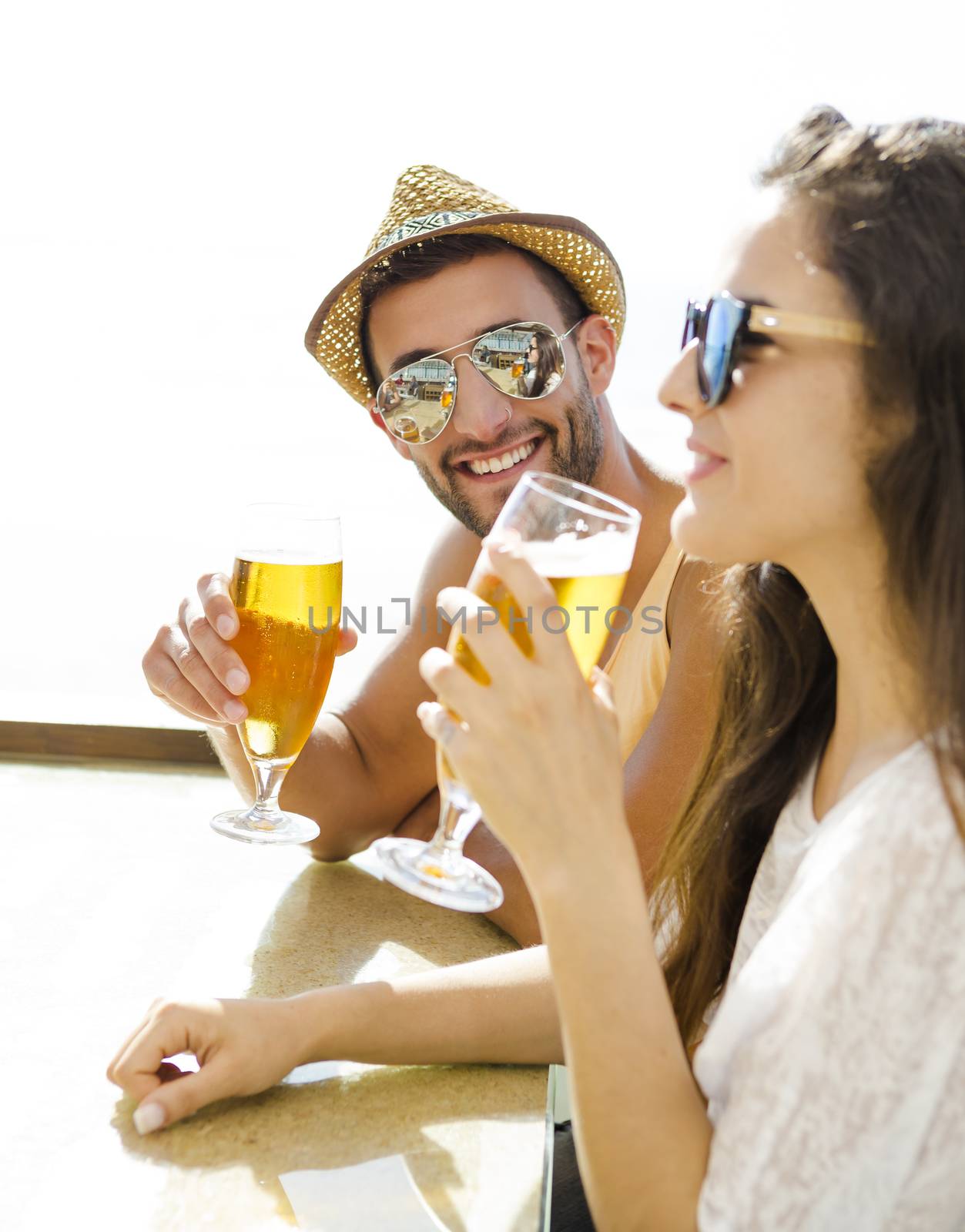 Friends having fun and drinking a cold beer at the beach bar