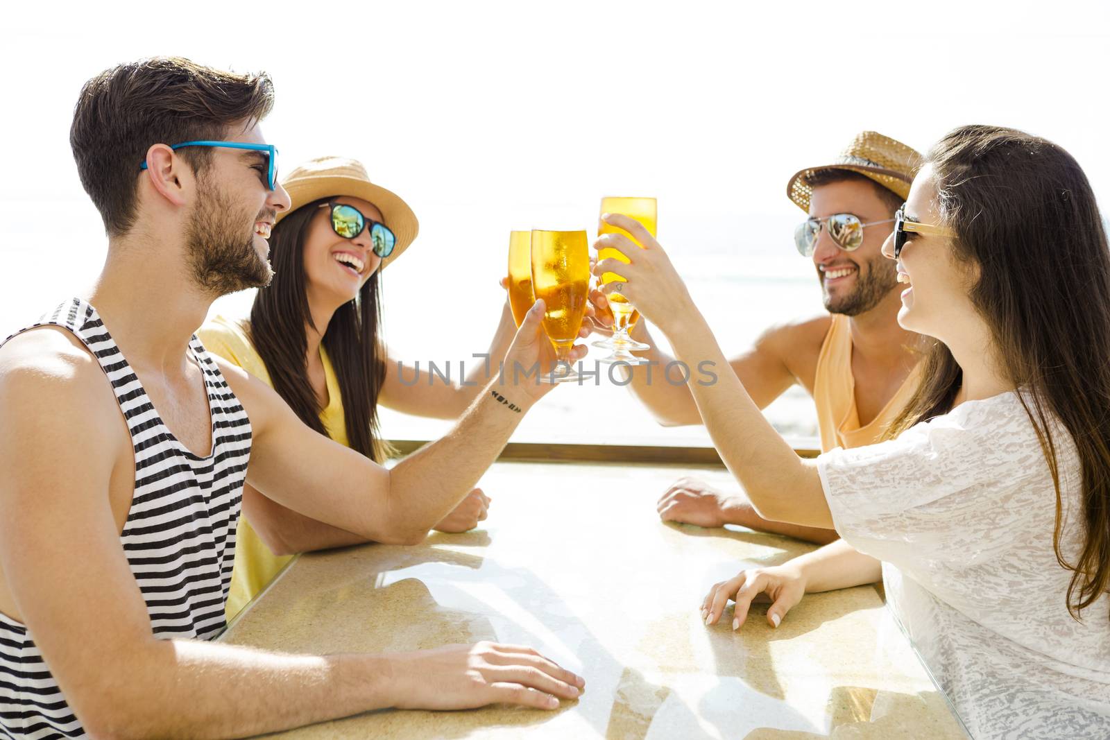 Friends having fun and drinking a cold beer at the beach bar