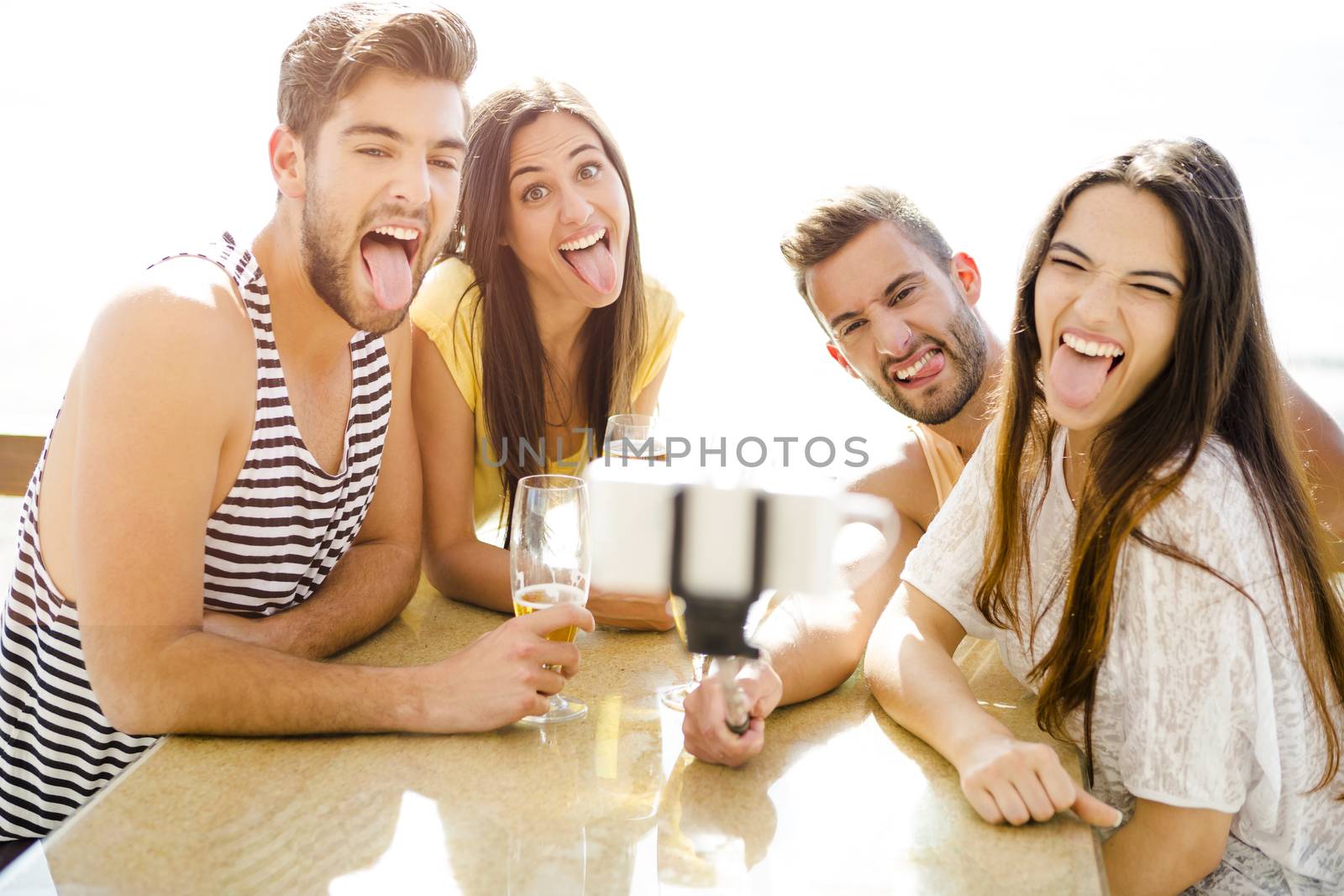 Group of friends at the beach bar and making a selfie