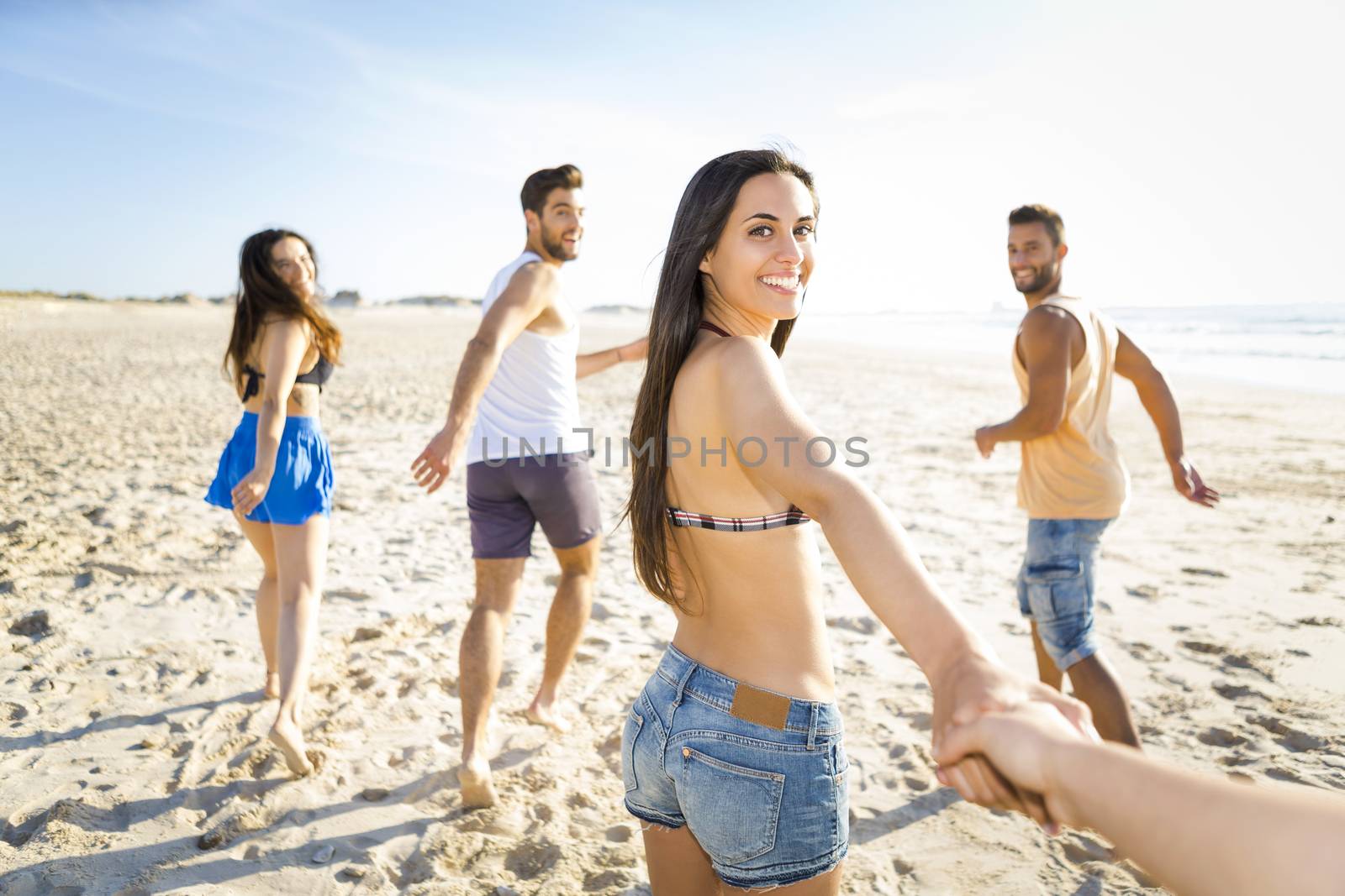 Group of friends running together at the beach and looking back