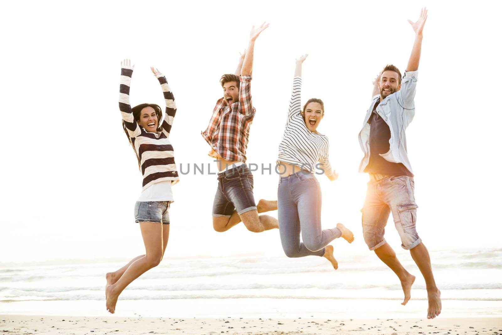 Group of friends making a jump together at the beach