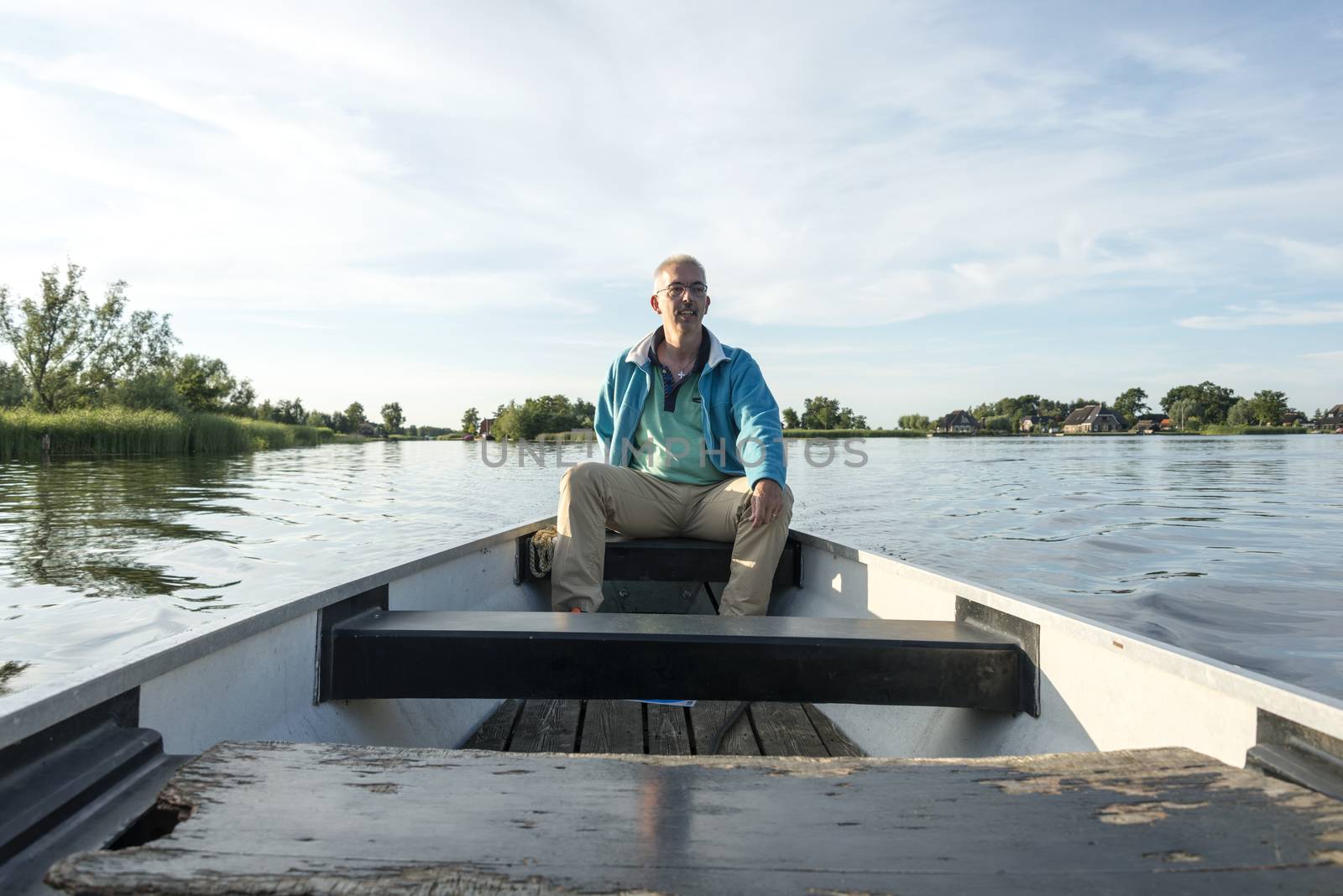 man on wooden boat on lake in the netherlands