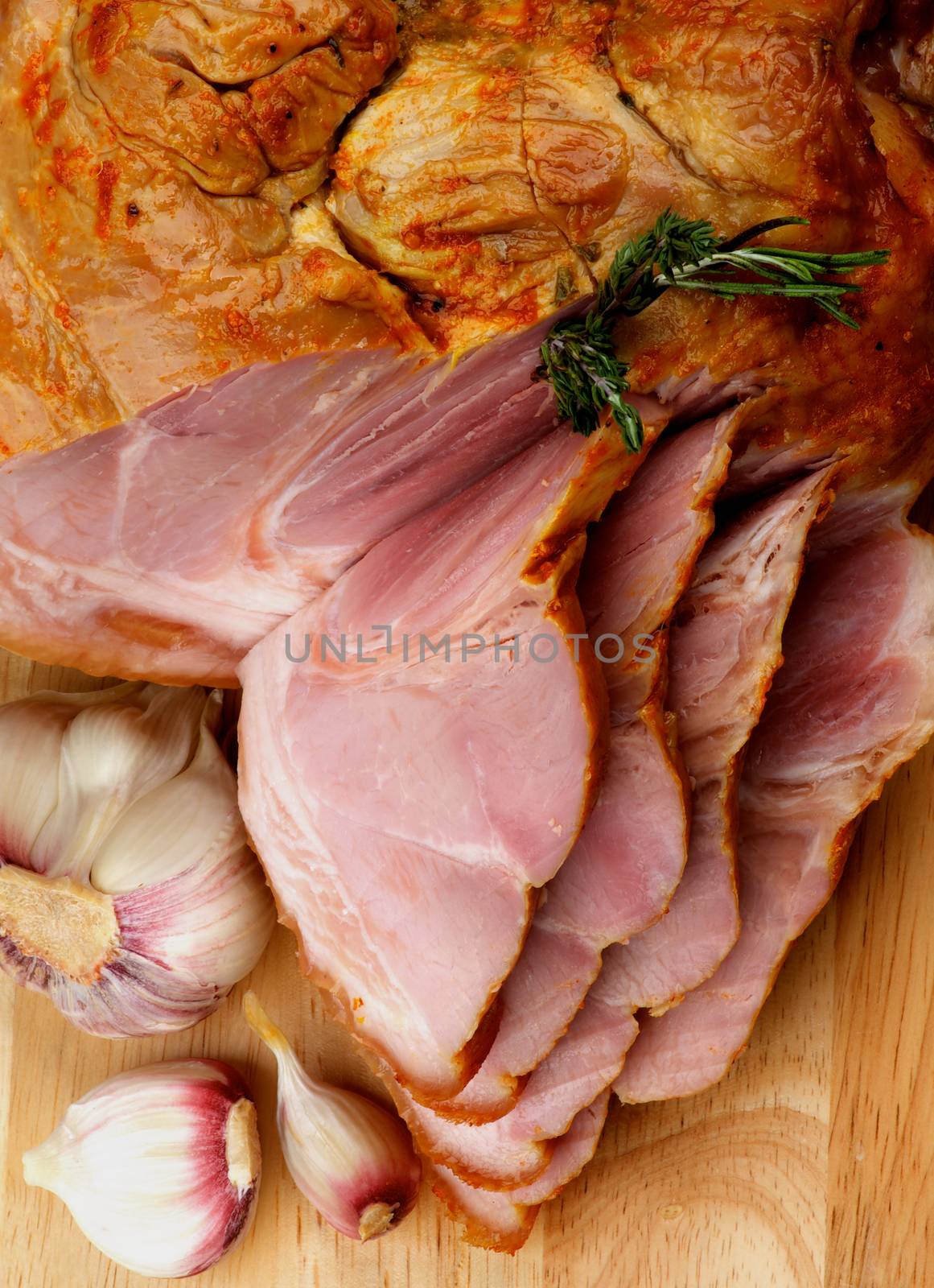 Full Body and Slices of Delicious Roasted Pork Knuckle Glazed with Spices and Garlic closeup on Cutting Board. Top View