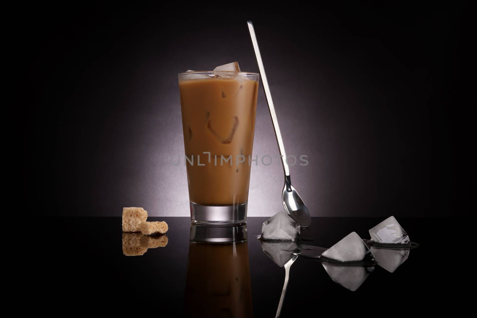 Delicious ice coffee with melting ice cubes and brown sugar on dark background. Culinary gourmet luxurious coffee drinking.