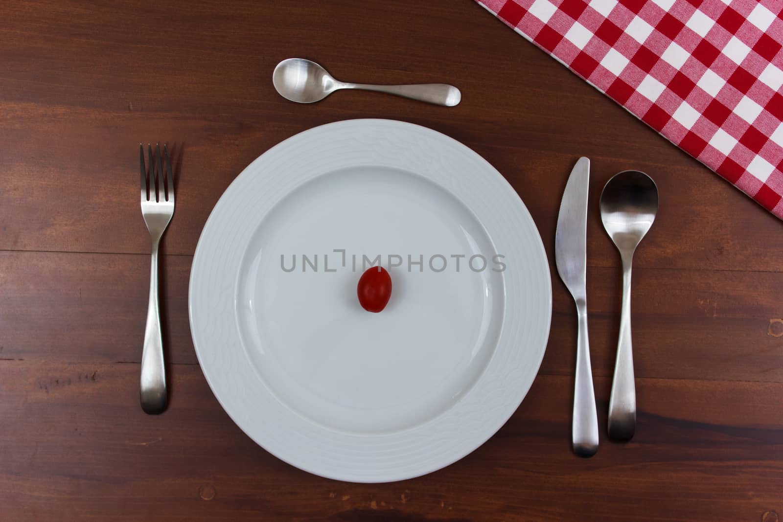 white plate with tomatoes on wooden table with cutlery