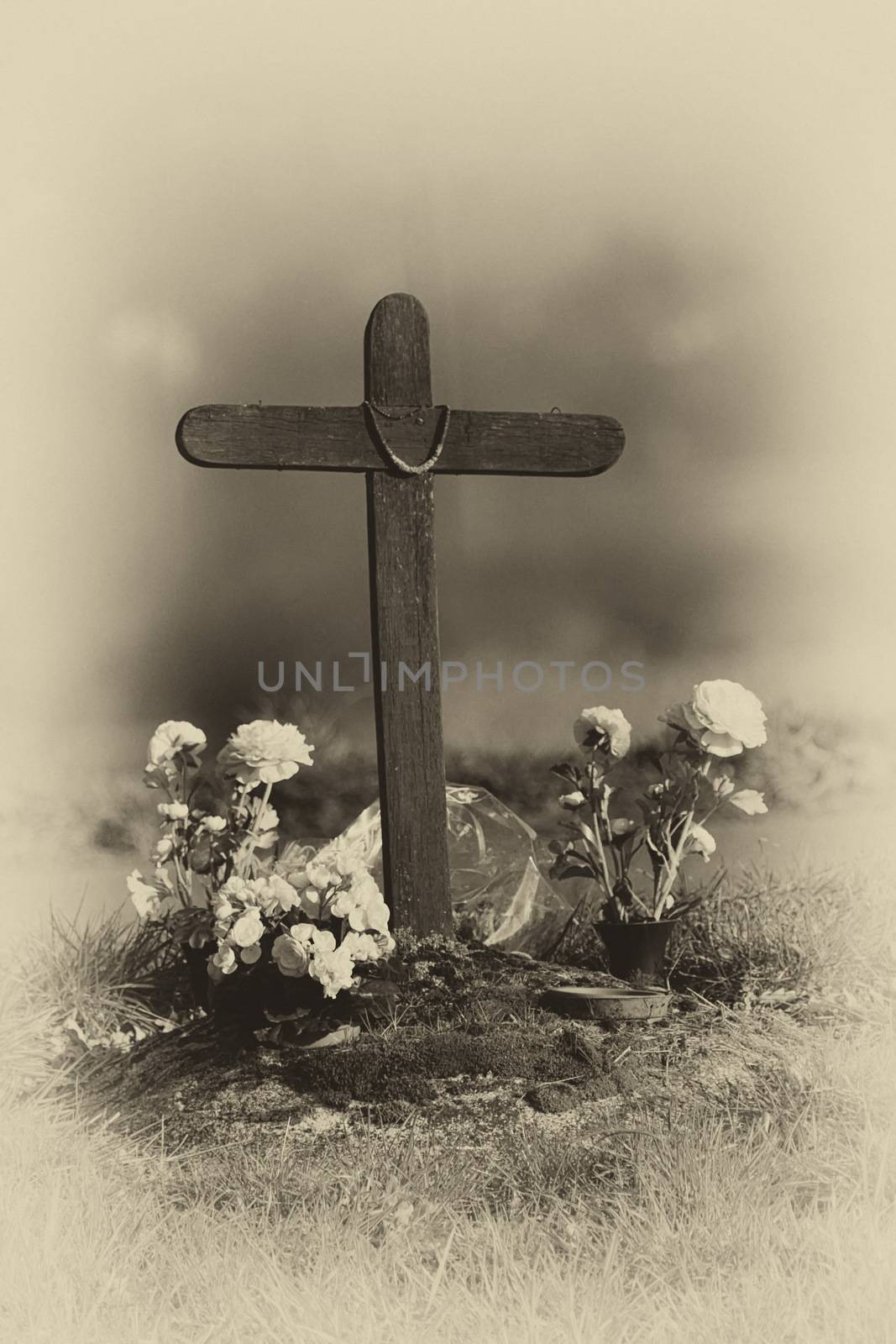 grave with flowers black and white and cross